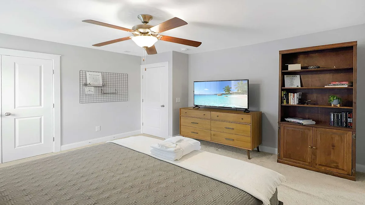 A tidy bedroom with a bed, TV, bookshelf, and dresser.