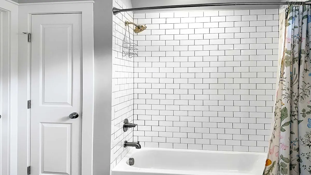 A clean bathroom with white subway tile, a white tub, and a floral shower curtain.