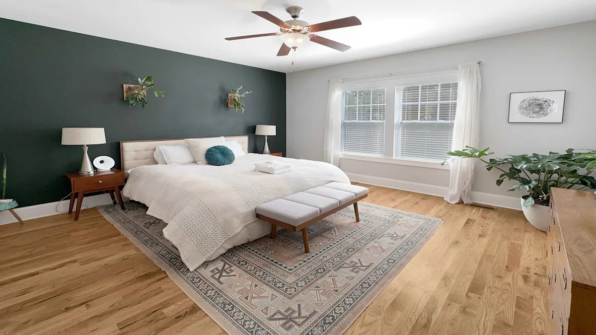A well-lit bedroom with a large bed, a window, and a ceiling fan.