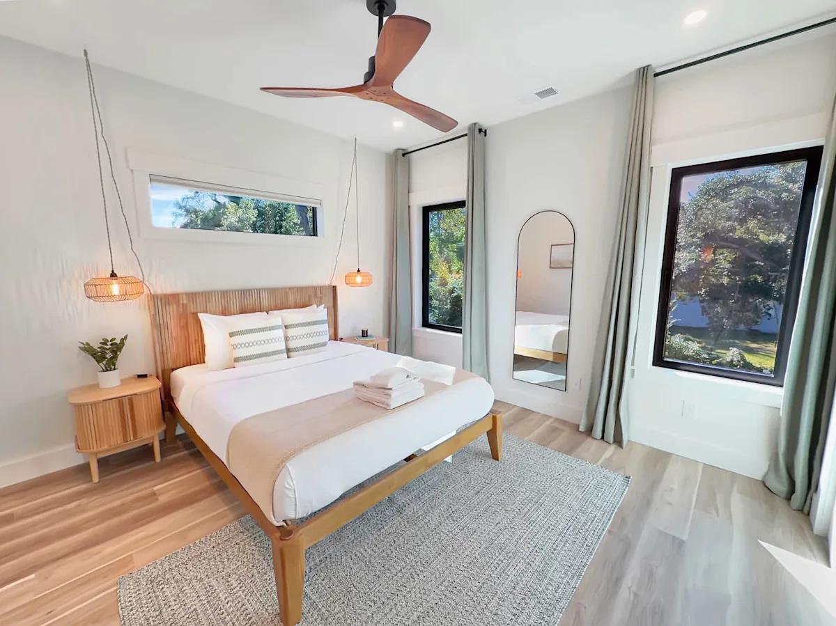 A clean and modern guest room with a bed, nightstand, and window