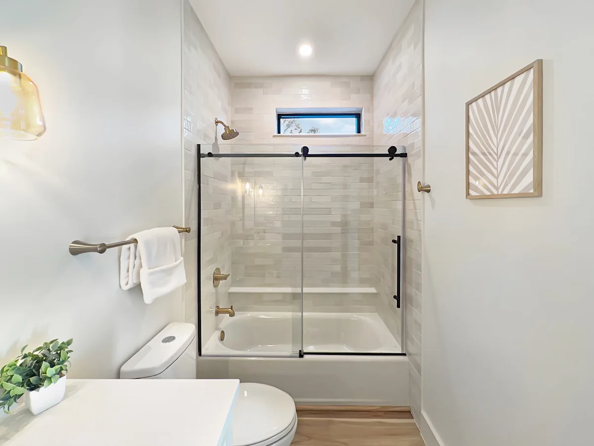 A clean and modern bathroom with a toilet, sink, and shower/bathtub combination.