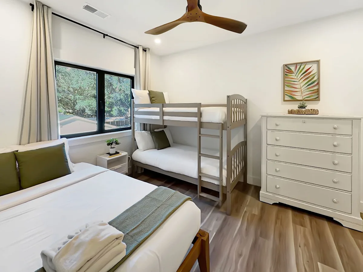 A bright and airy room with a bunk bed, dresser, and window