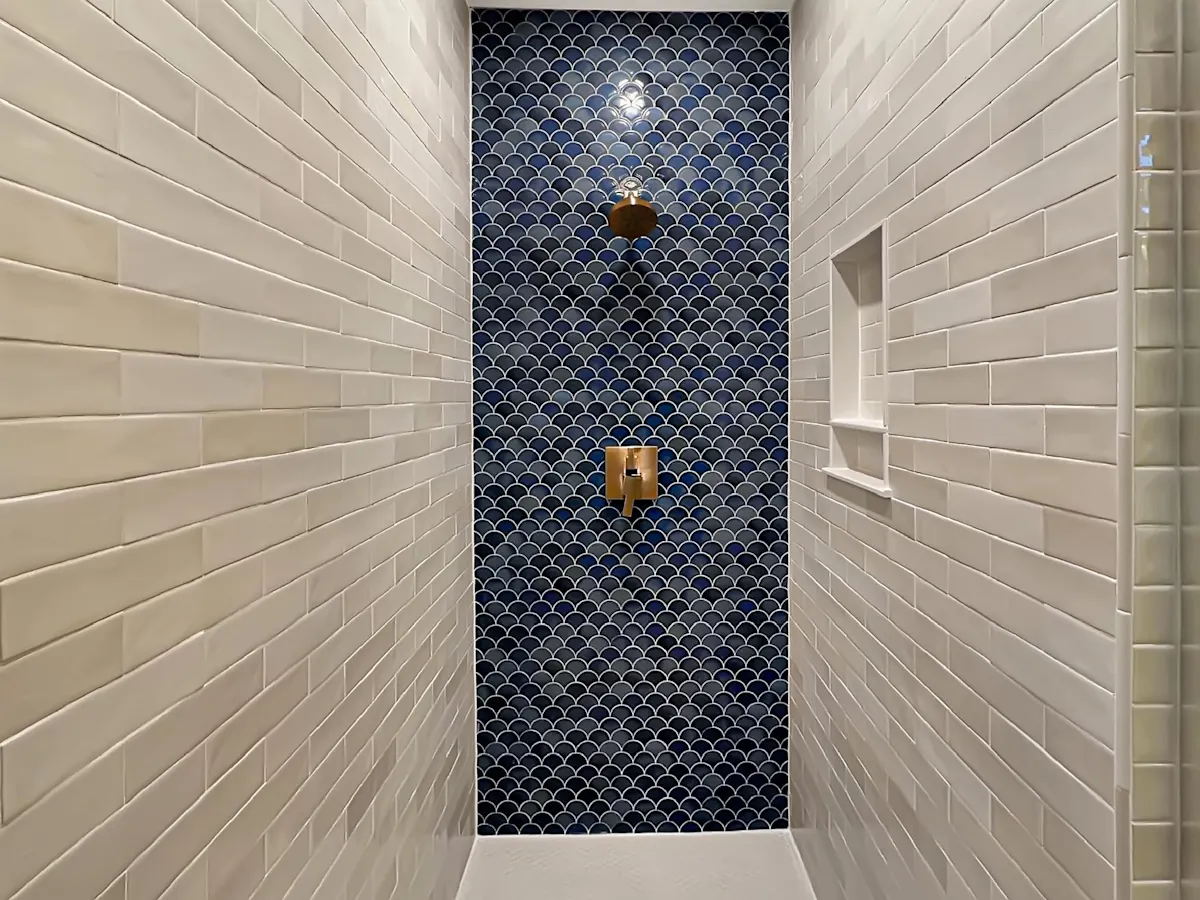 A shower with white tile walls and a blue accent wall