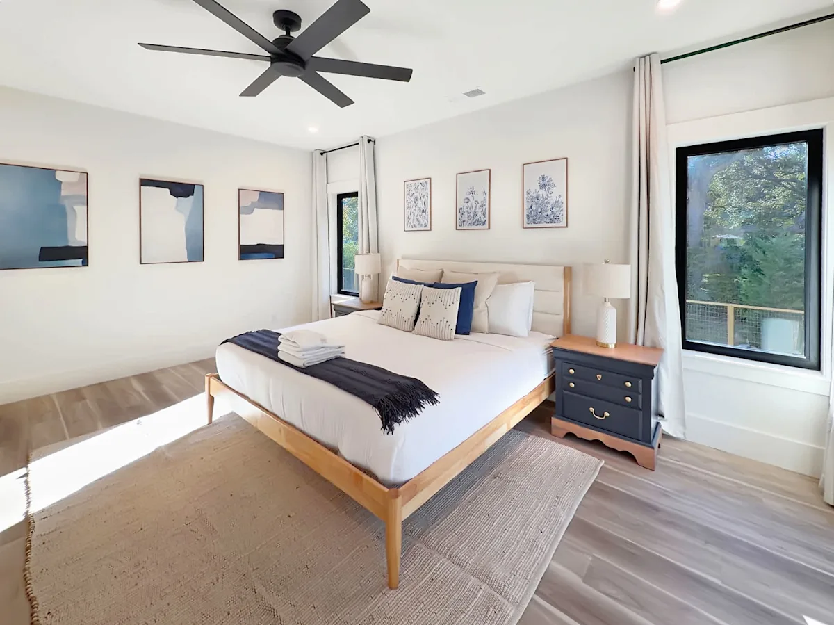 A wide-angle view of a bedroom with a bed, nightstand, and window.