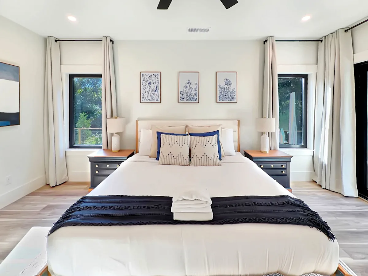 A wide view of a bedroom with a large bed, two nightstands, and three pieces of artwork on the wall.