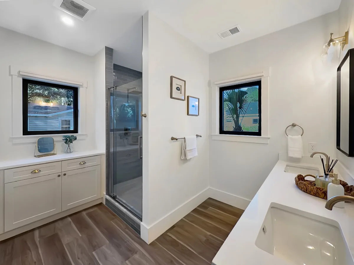A modern bathroom with a shower, sink, and cabinet.