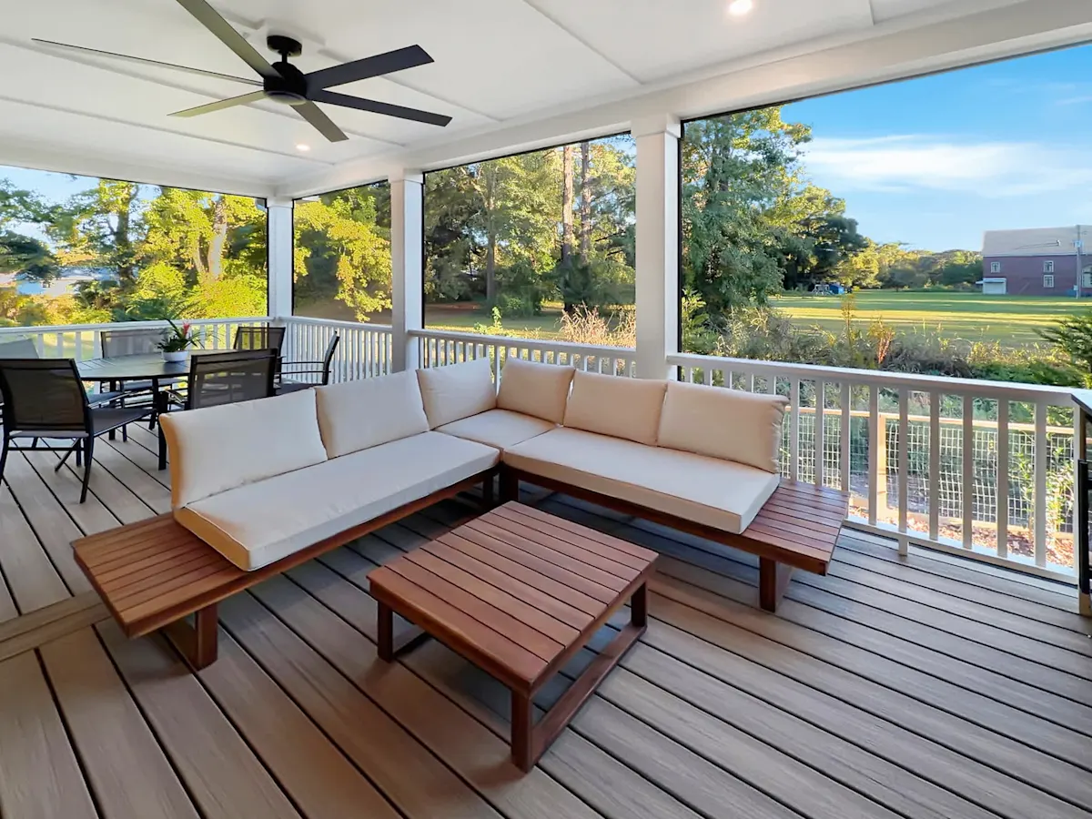 A screened-in porch with outdoor furniture and a ceiling fan