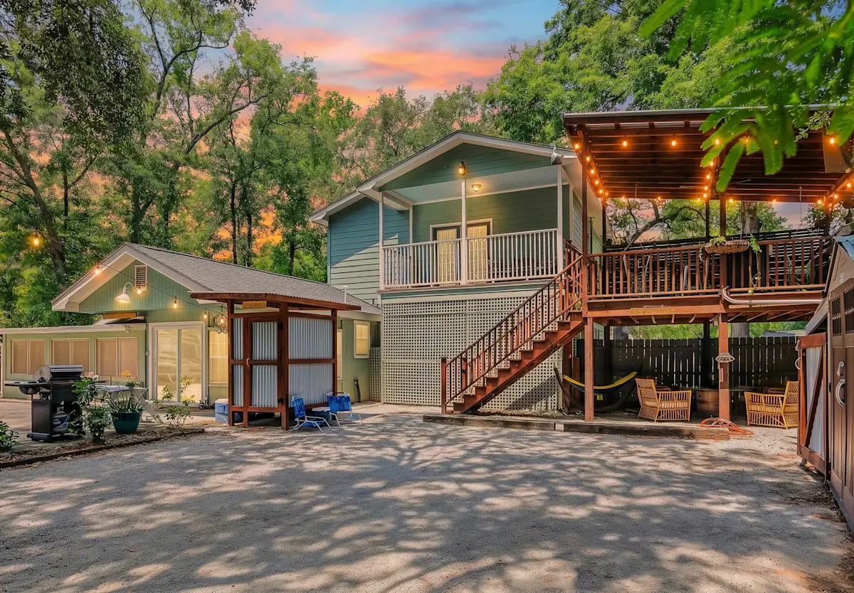 A green house with a deck and stairs under a colorful sky