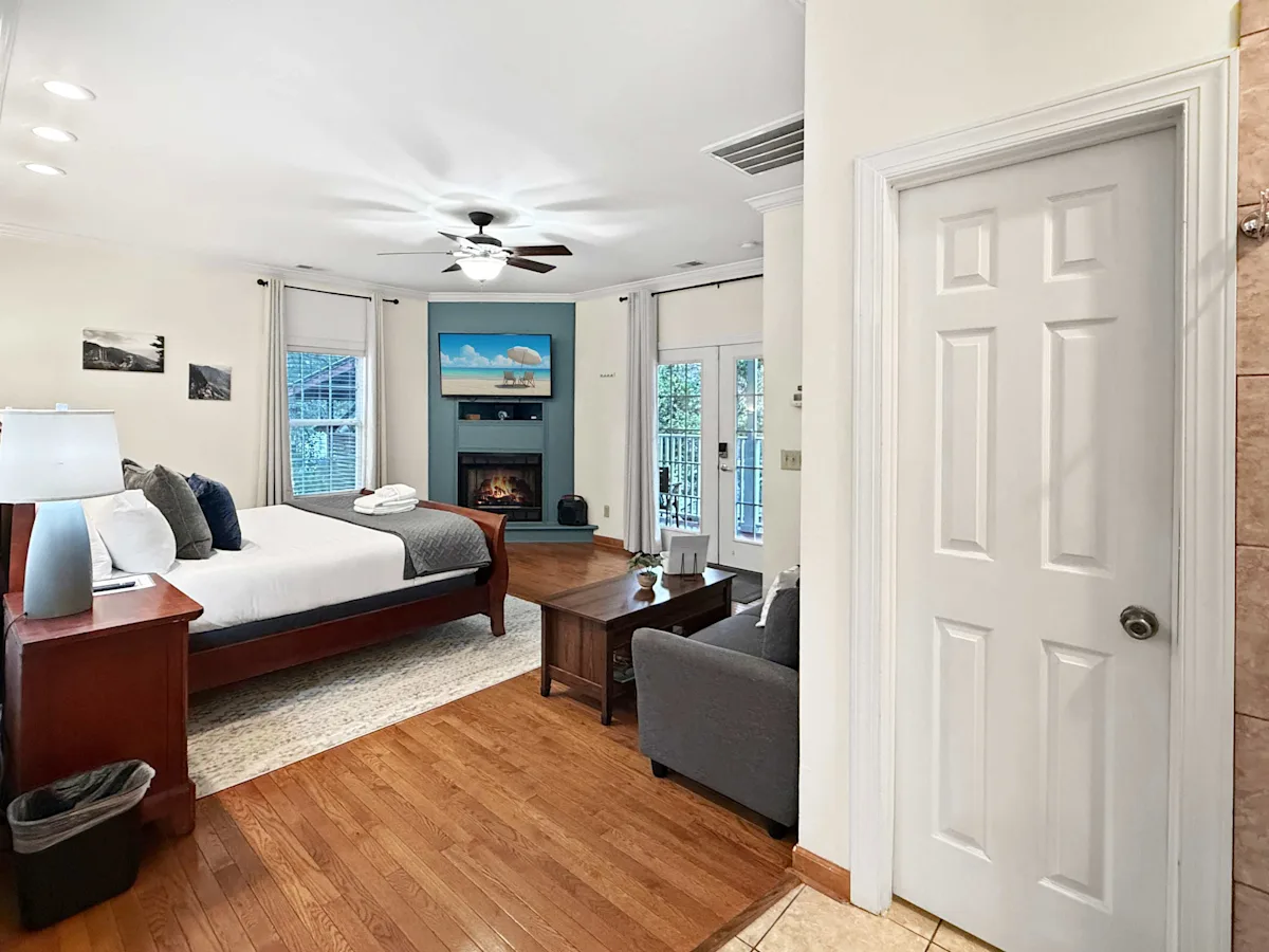 A wide view of a hotel room with a bed, sofa, fireplace, and TV.
