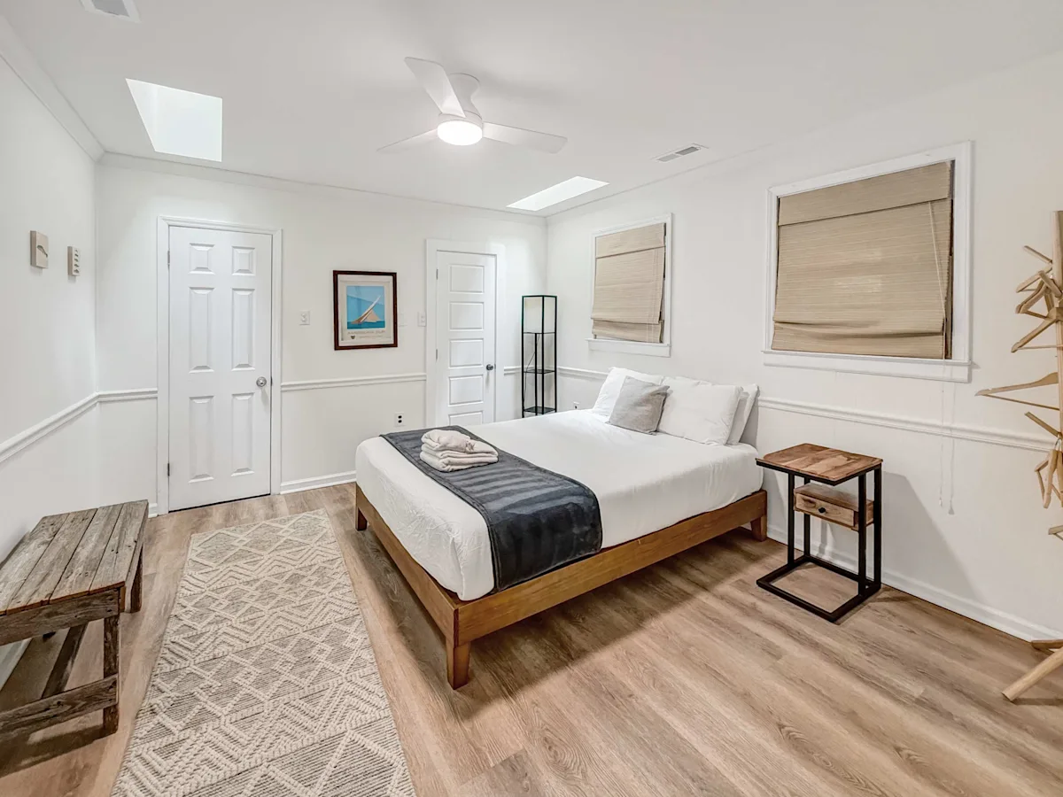 A wide view of a hotel room with a bed, nightstand, and bench.