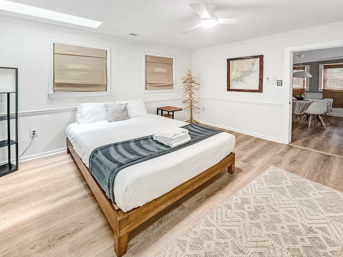 A wide view of a hotel room with a bed, window, and artwork.