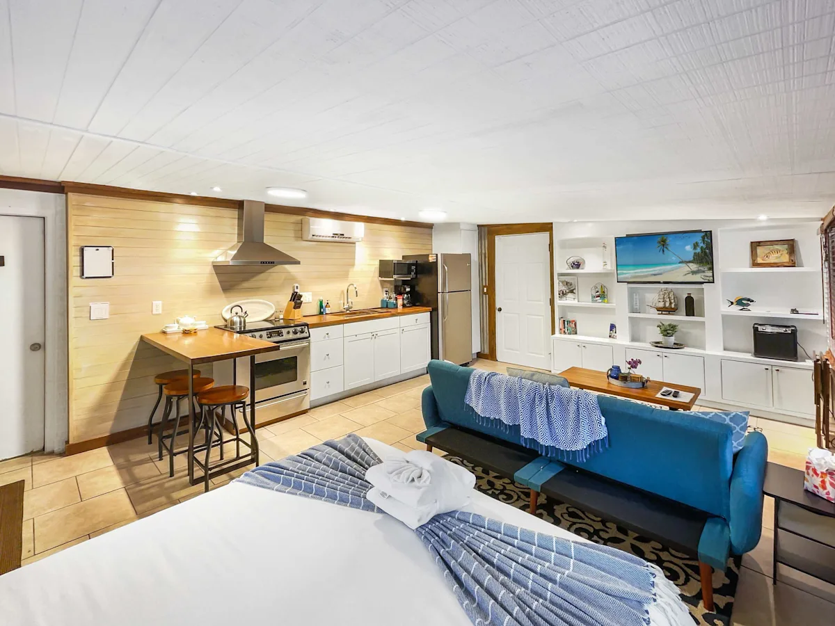 A wide view of a suite with a kitchenette, living area, and bed.