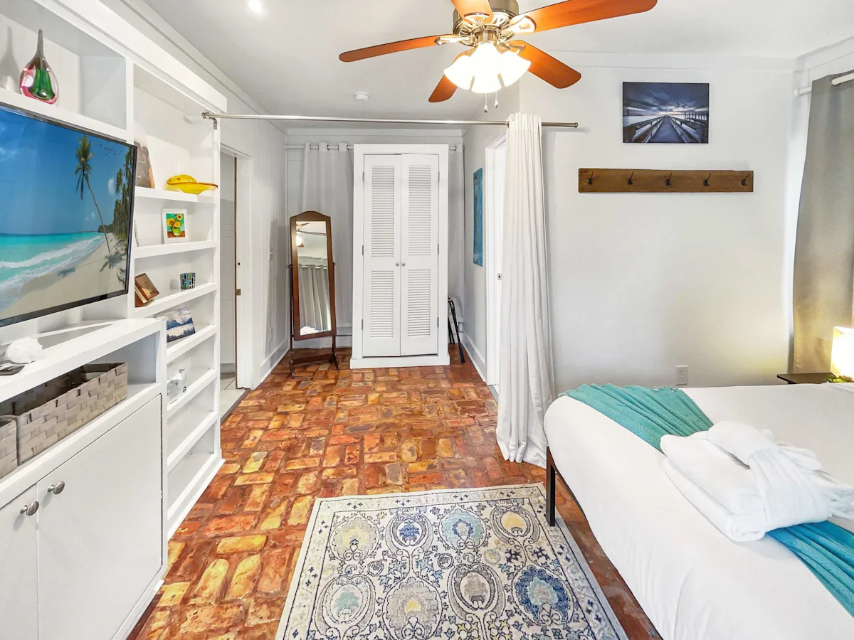 A wide view of a hotel room with a bed, TV, and shelves.