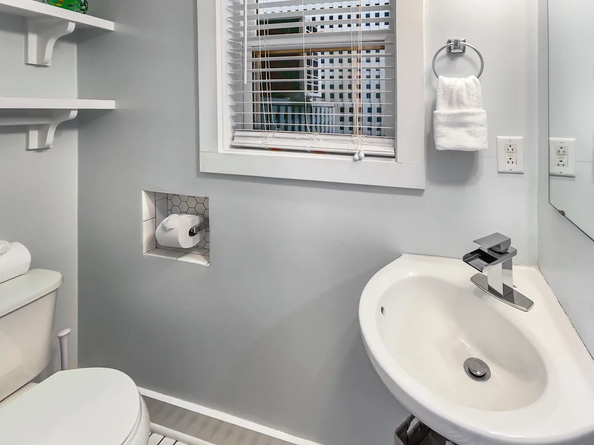 A bathroom with a toilet, sink, and window