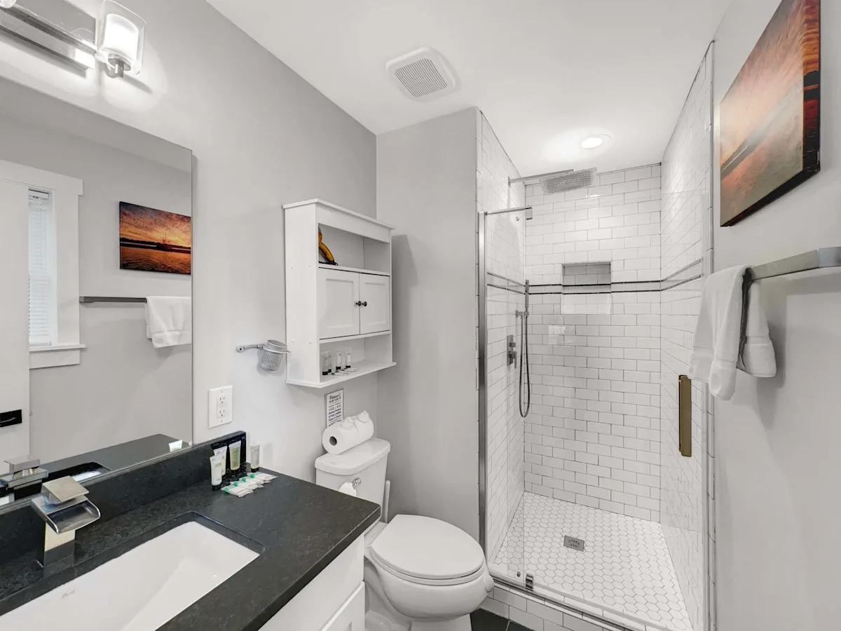 A clean bathroom with a shower, toilet, sink, and mirror.