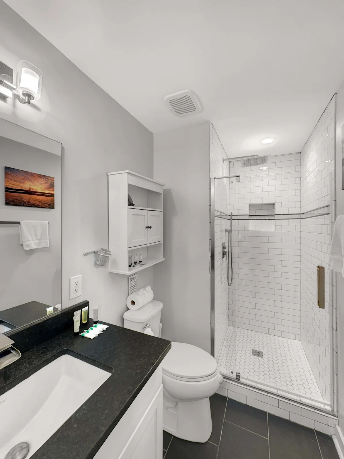A clean and modern bathroom with a shower, toilet, vanity, and mirror.
