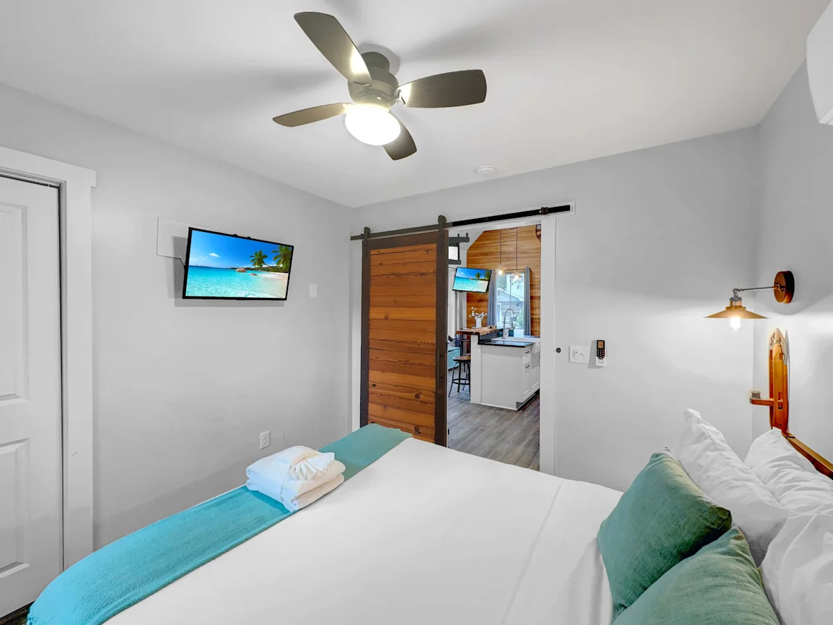 A hotel room with a bed, TV, and sliding barn door to kitchenette