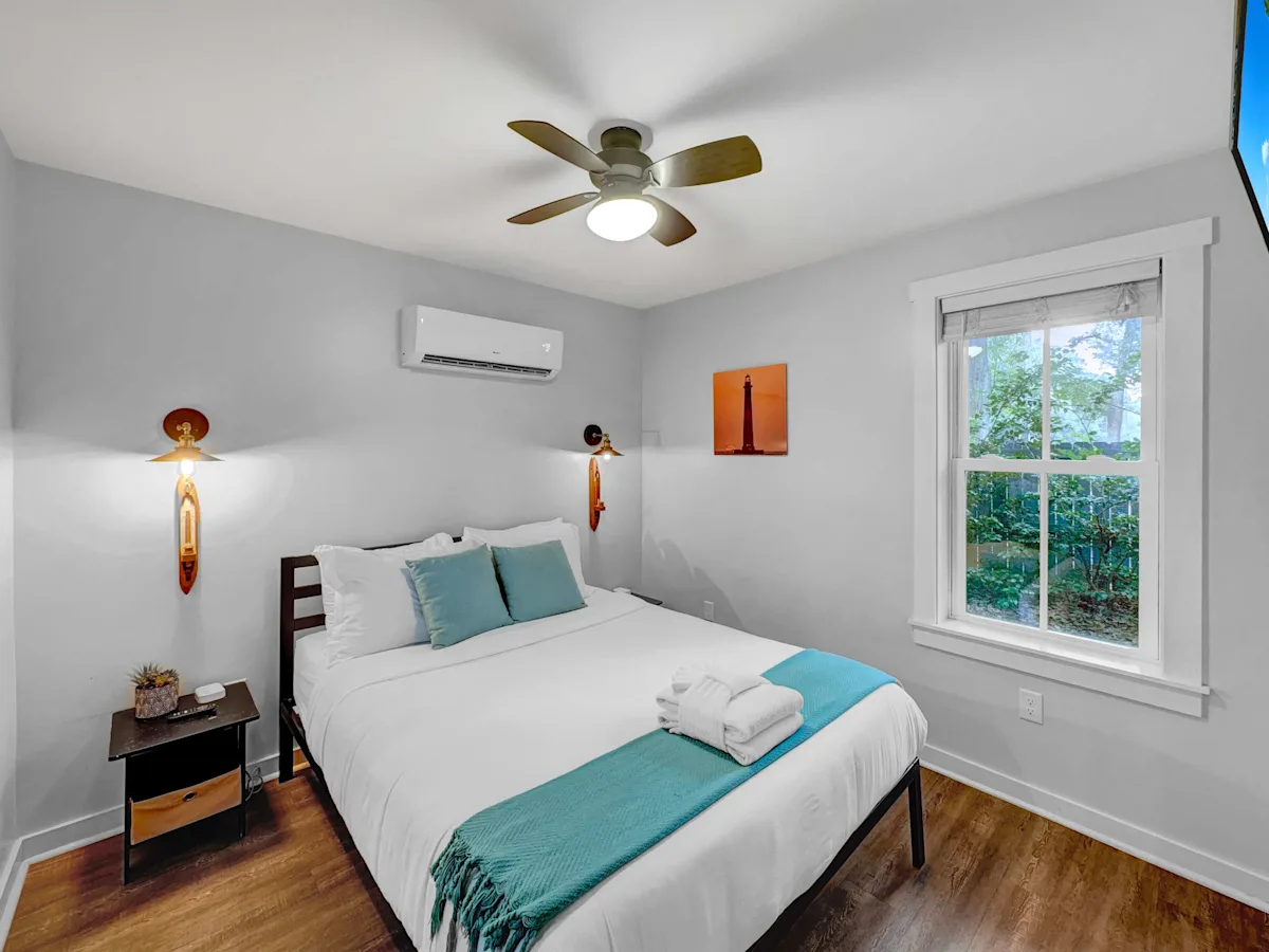 A clean and cozy guest room with a bed, nightstand, and window.
