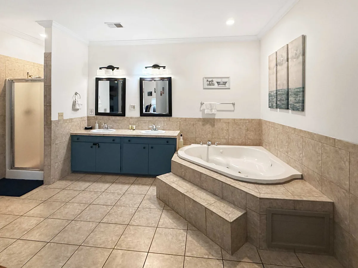A large bathroom with a double vanity, jacuzzi tub, and shower.