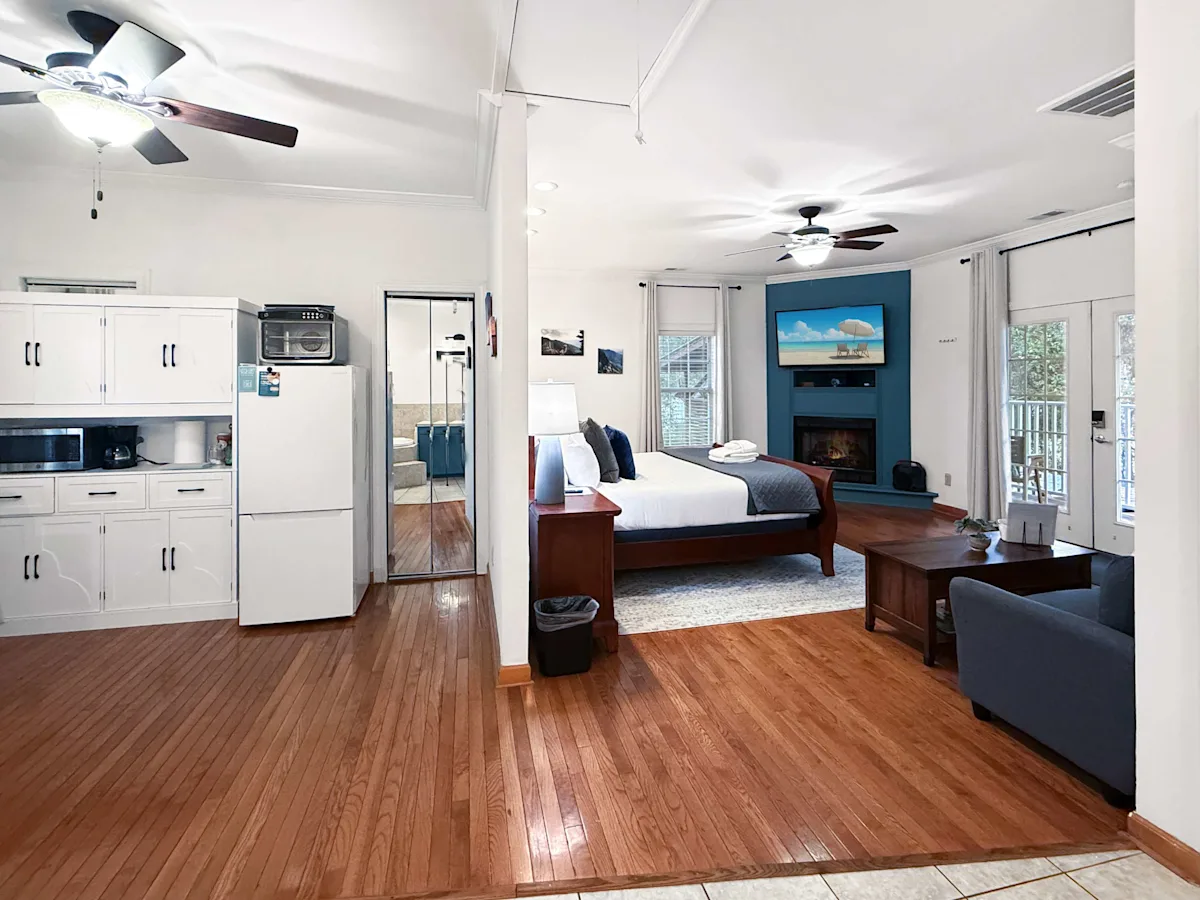 A wide view of a suite with a kitchenette, living area, bedroom, and fireplace.