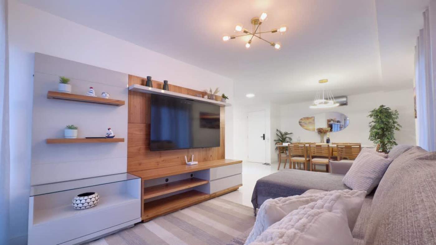 Sala espaçosa com TV Smart, sofá confortável e integração com a mesa de jantar para até 8 pessoas.