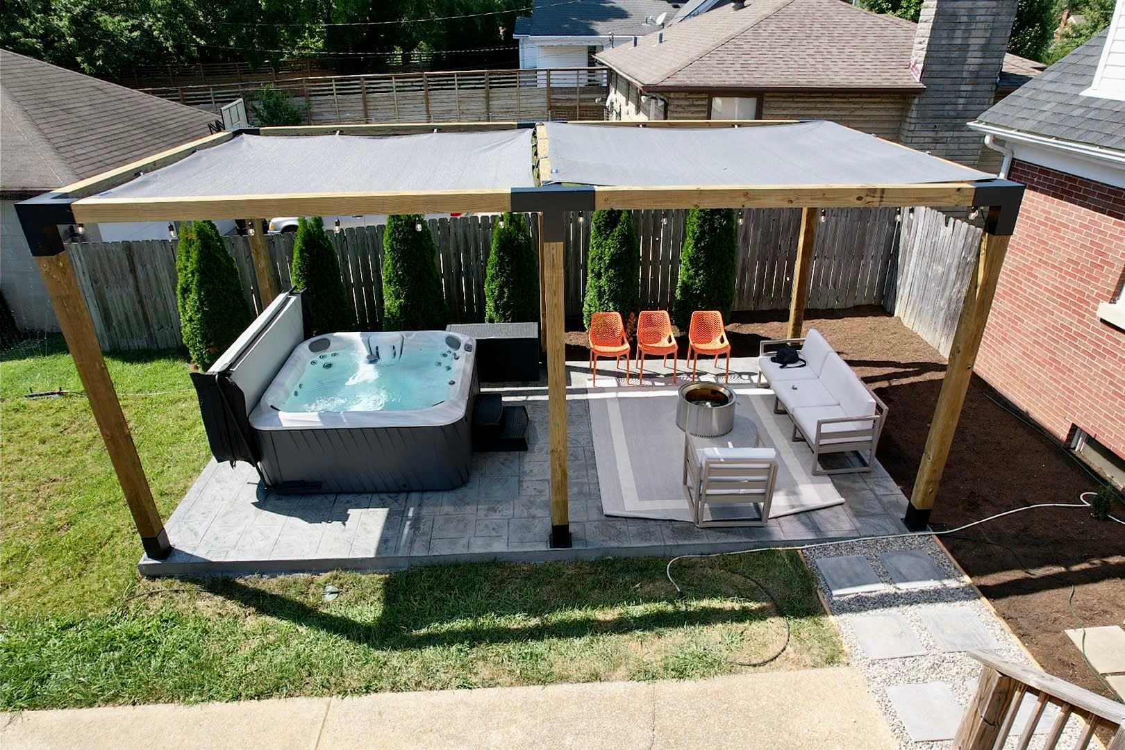 Step outside and you're basically off the grid — arborvitae hedges block the neighbors, hot tub and fire pit tucked into their own private pergola corner.