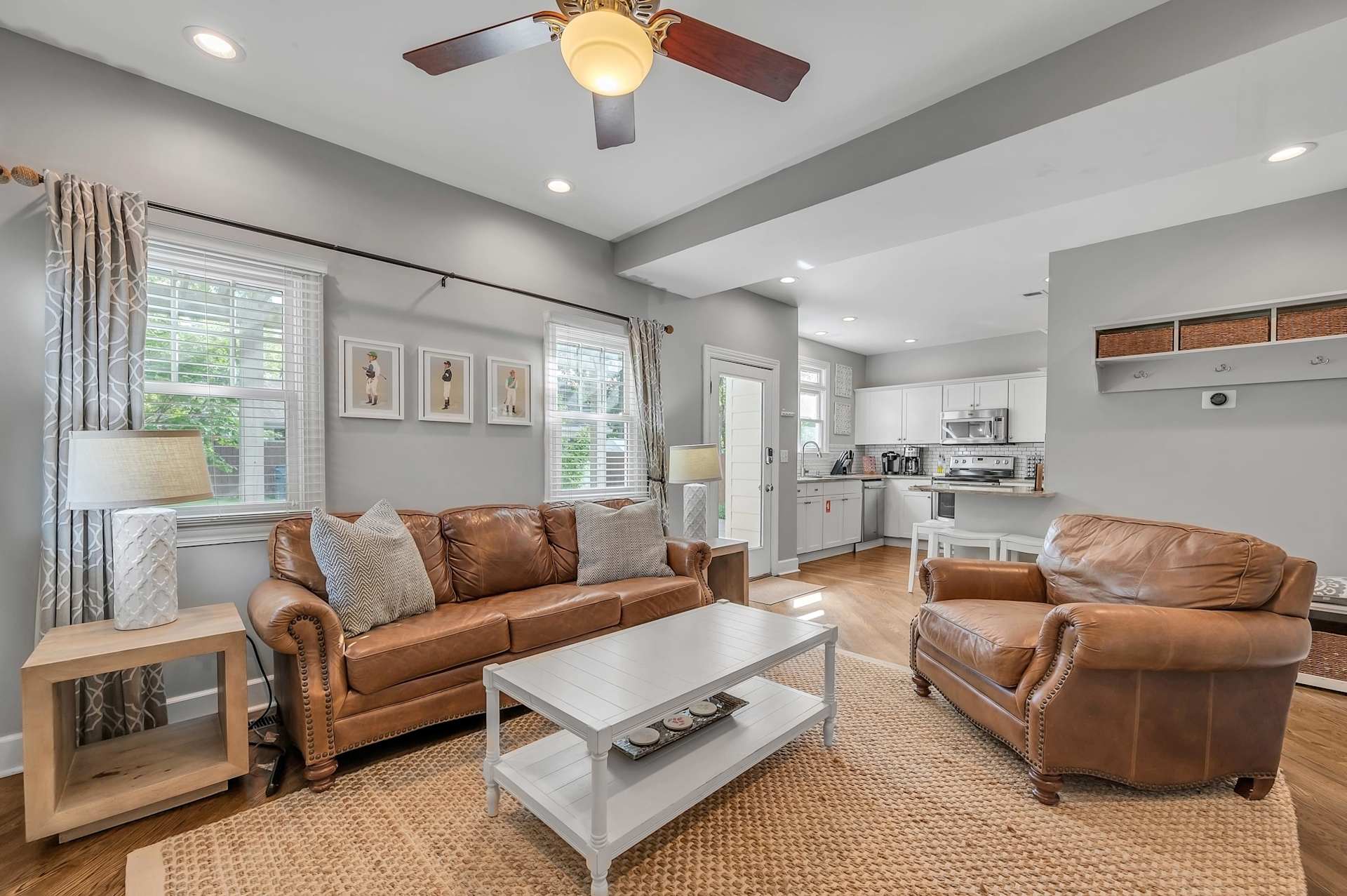 Open-concept living room with leather seating and a smart TV, flowing into the kitchen.