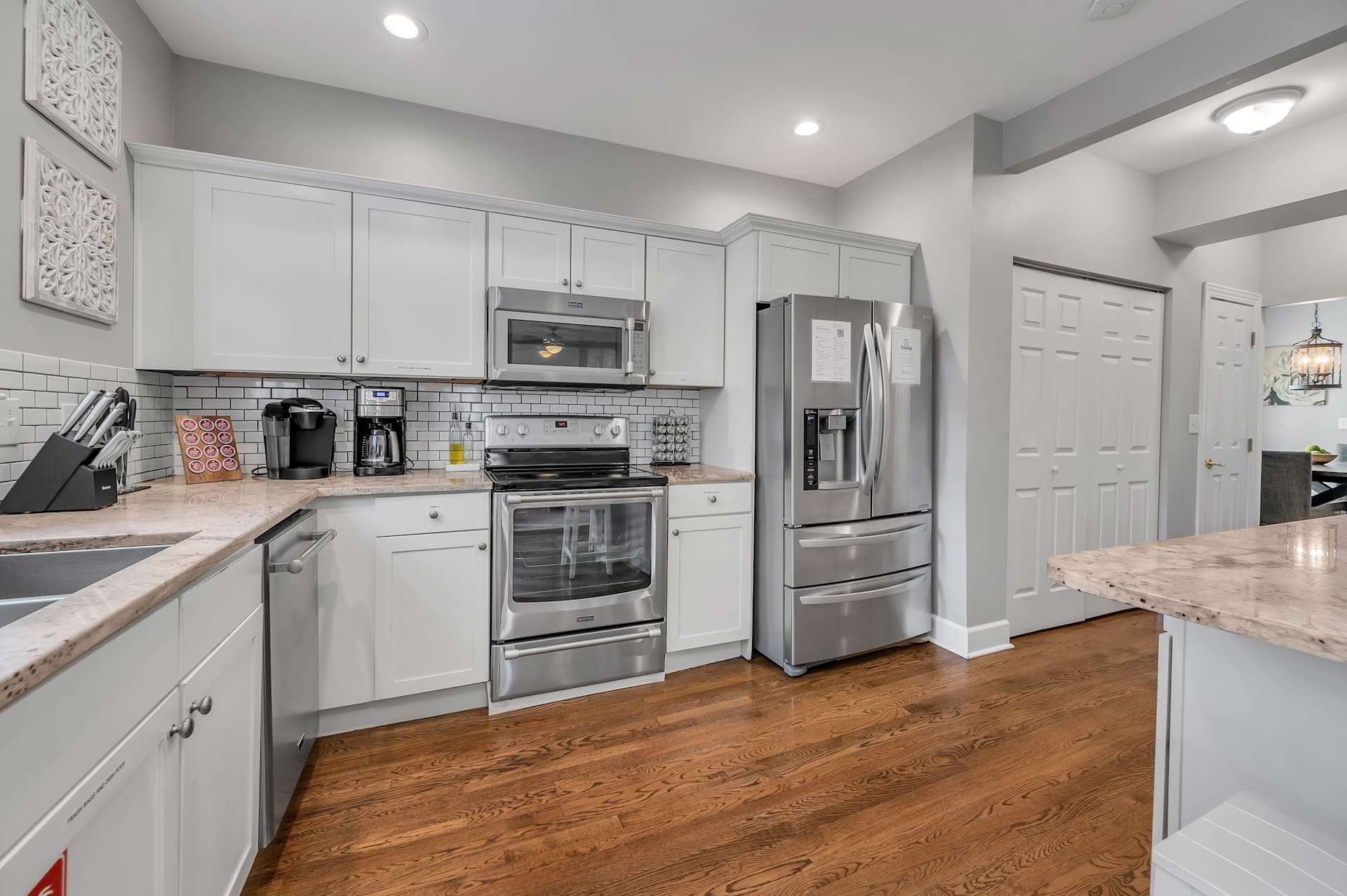 Bright, updated white kitchen with stainless appliances and stone counters.