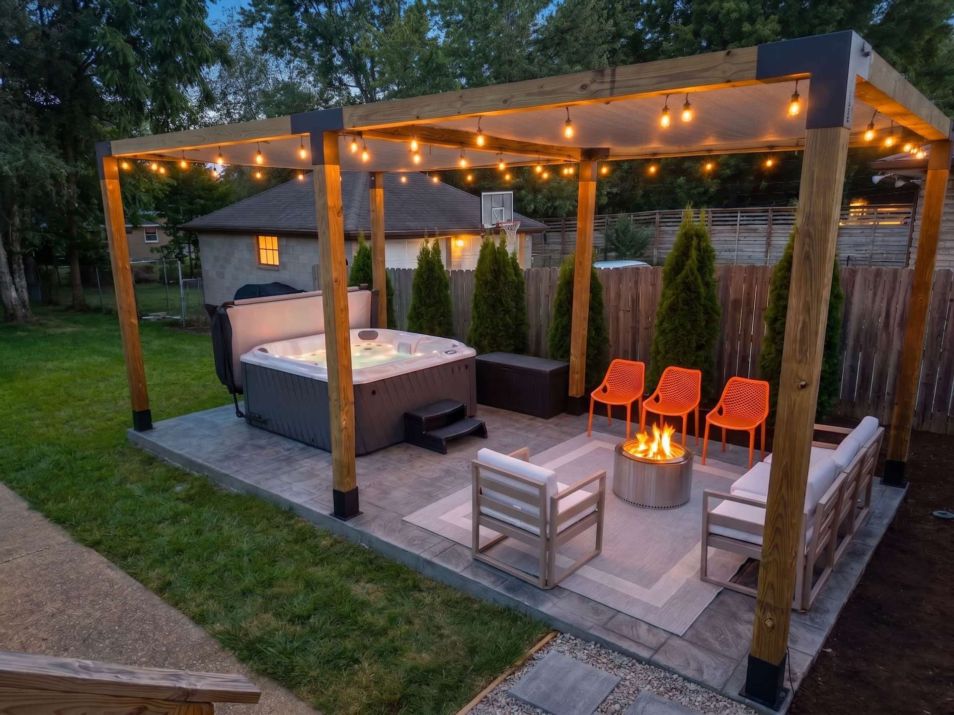 Pull two chairs up to the fire pit while the hot tub steams a few feet away — string lights overhead, the whole pergola built for exactly this kind of night.