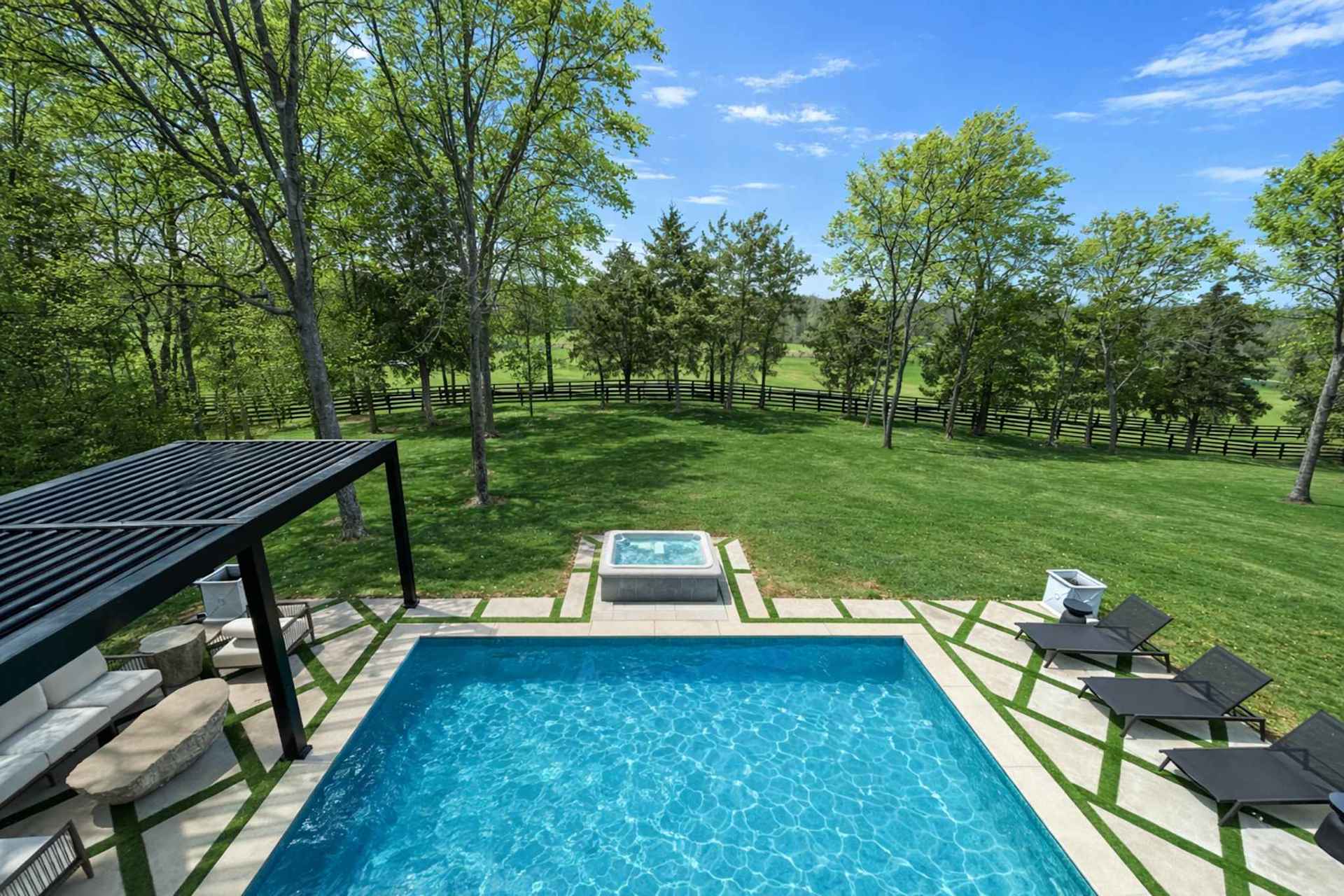 Look down at the pool deck from above and you'll see why this property books early — rectangular pool, hot tub at the end, pergola lounge in the corner. Your private resort.