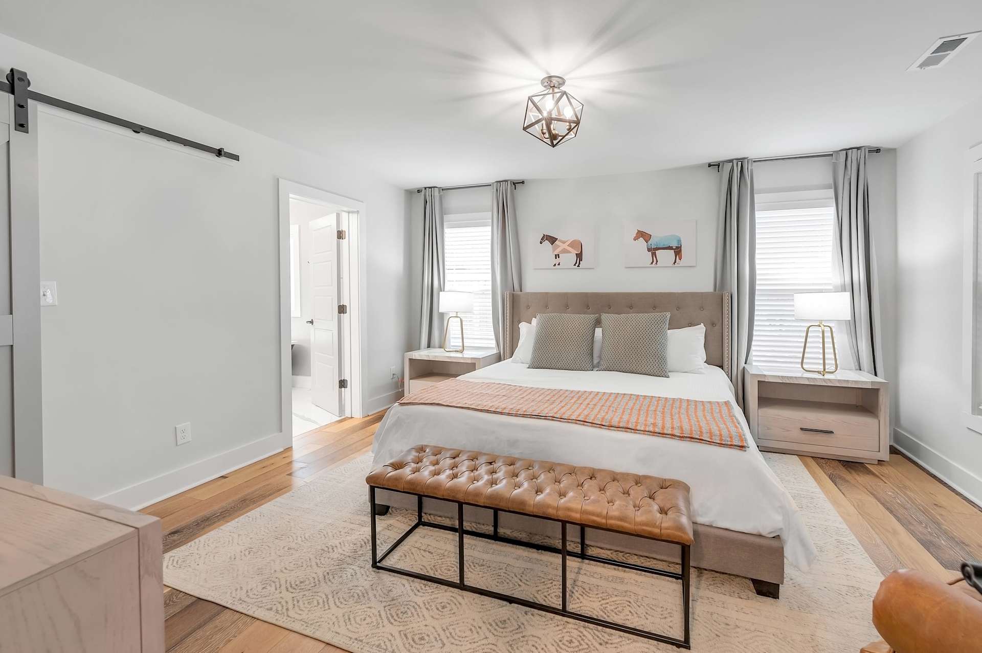 Sleep in the suite with its own barn door — slide it open and the ensuite bath is right there, a bench at the foot of the bed for dropping your bags.