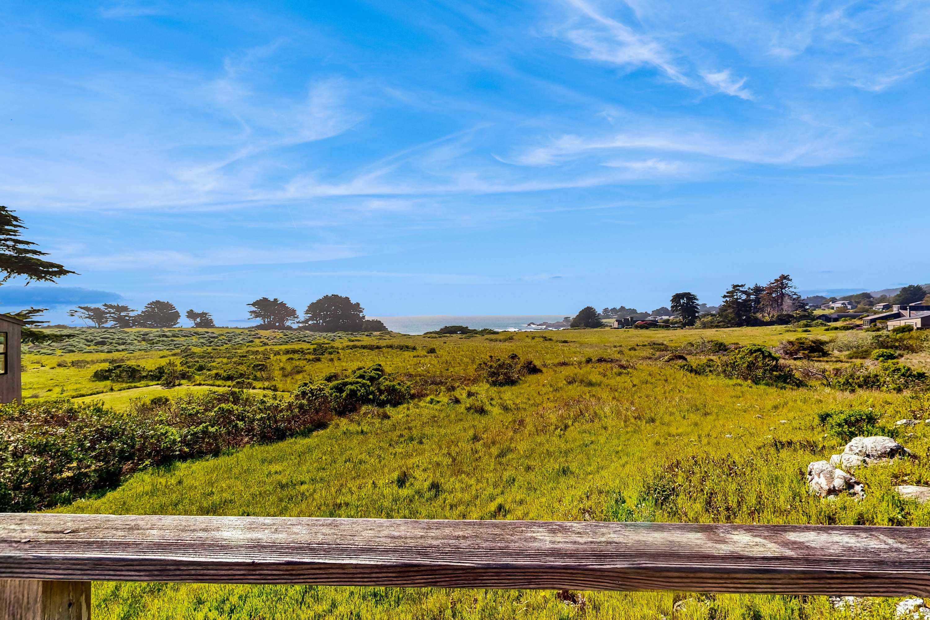 The serene landscape invites you to explore, with lush meadows leading your eyes to the horizon where the ocean meets the sky.