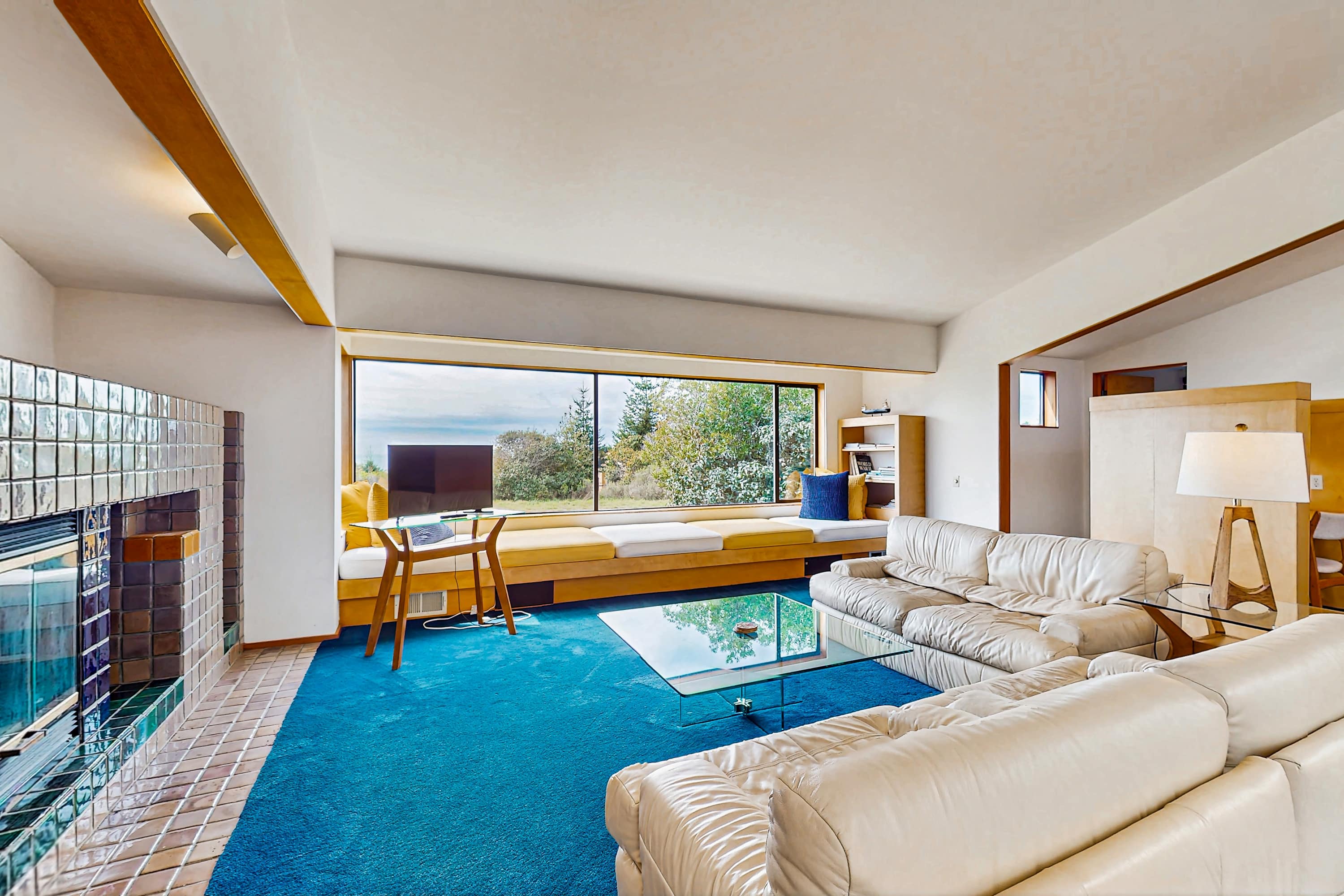 Bask in natural light while lounging in style; this cozy living room is perfect for unwinding with ocean views and a crackling fire.