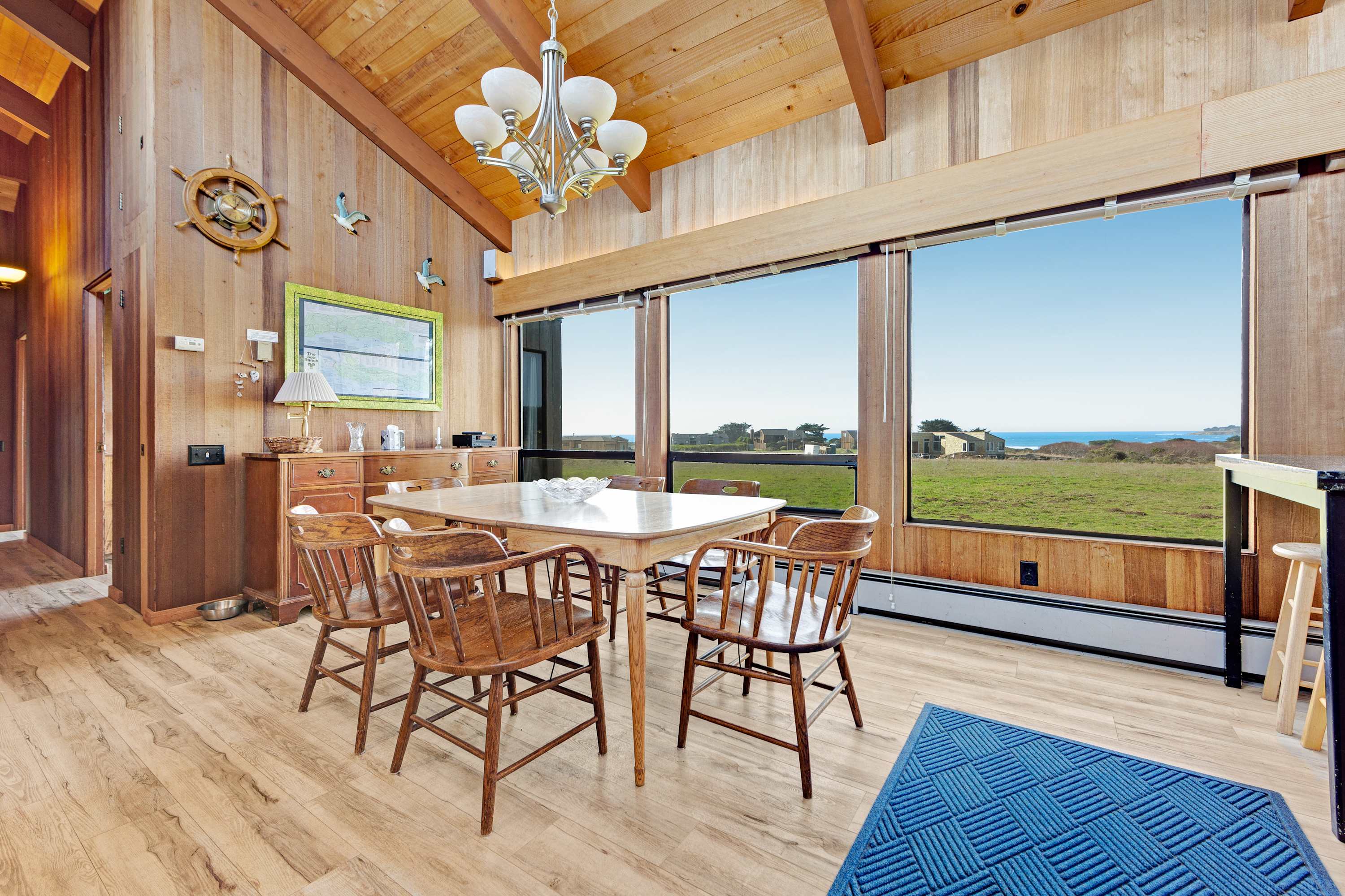 Share laughter and meals in this dining area, complete with panoramic windows that frame ocean views and the lush landscape.