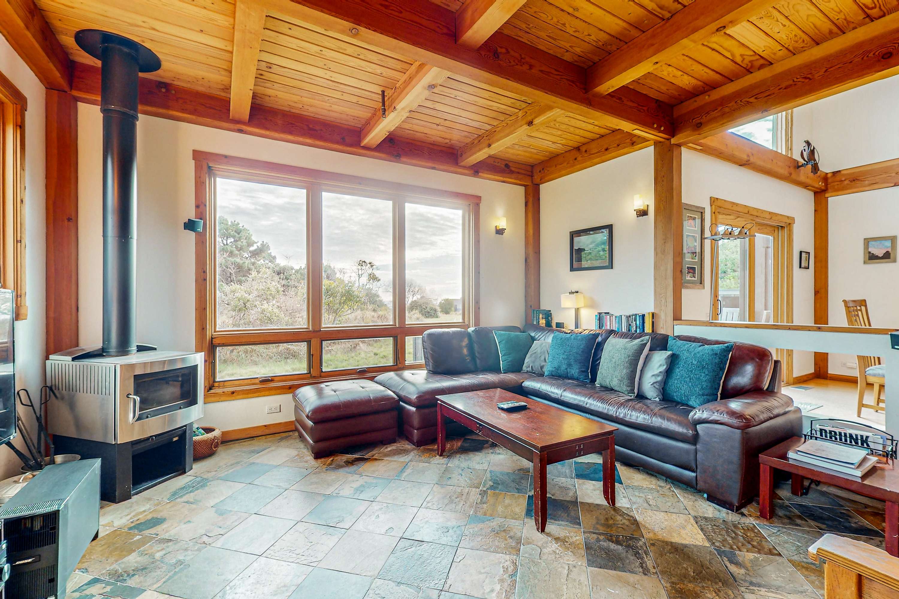 Gather around the warmth of the gas fireplace in this inviting living room, where natural light dances off the wood beams and offers views of the serene landscape.