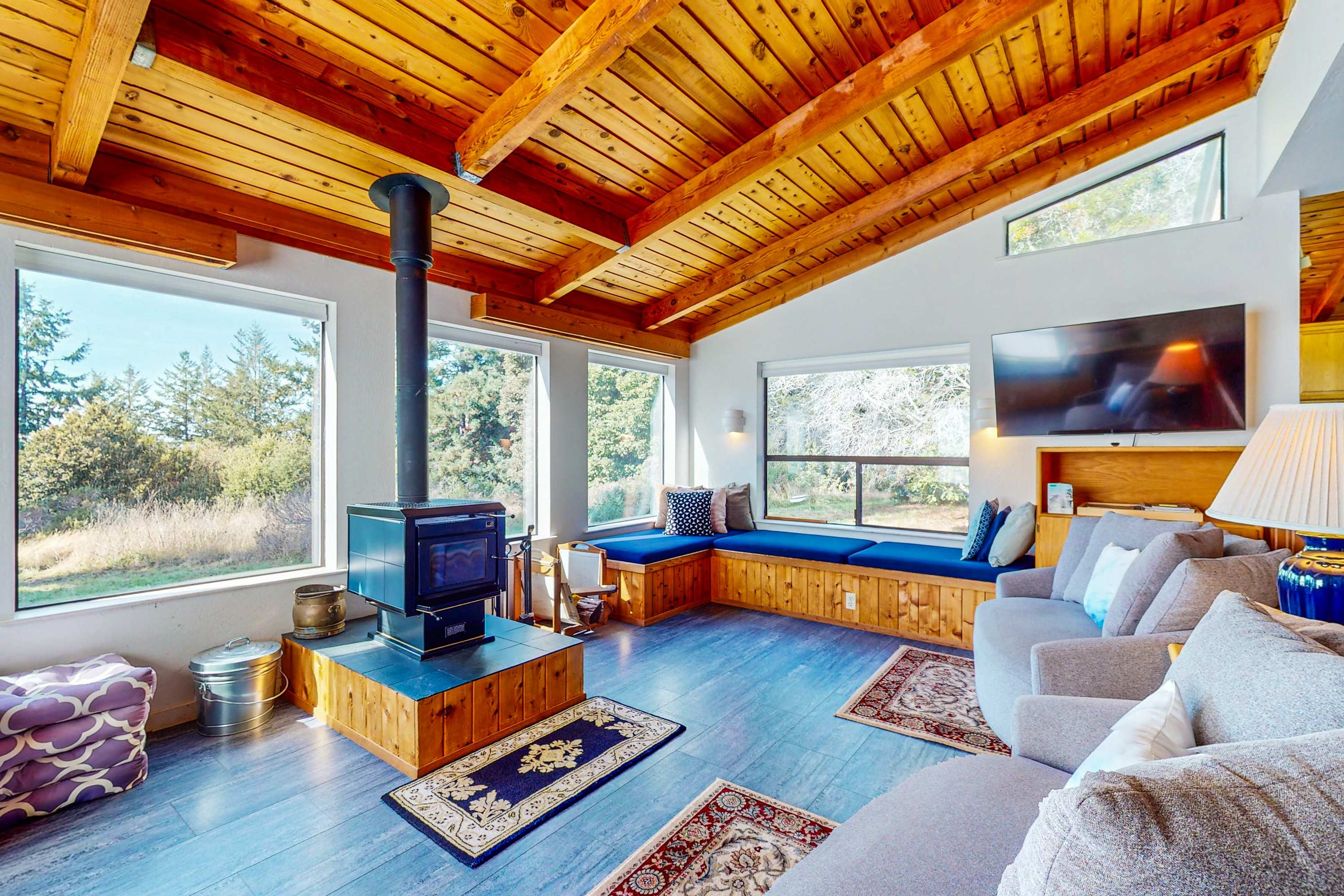 Gather around the cozy fireplace in the living room, where natural light filters through expansive windows, inviting warmth and relaxation.