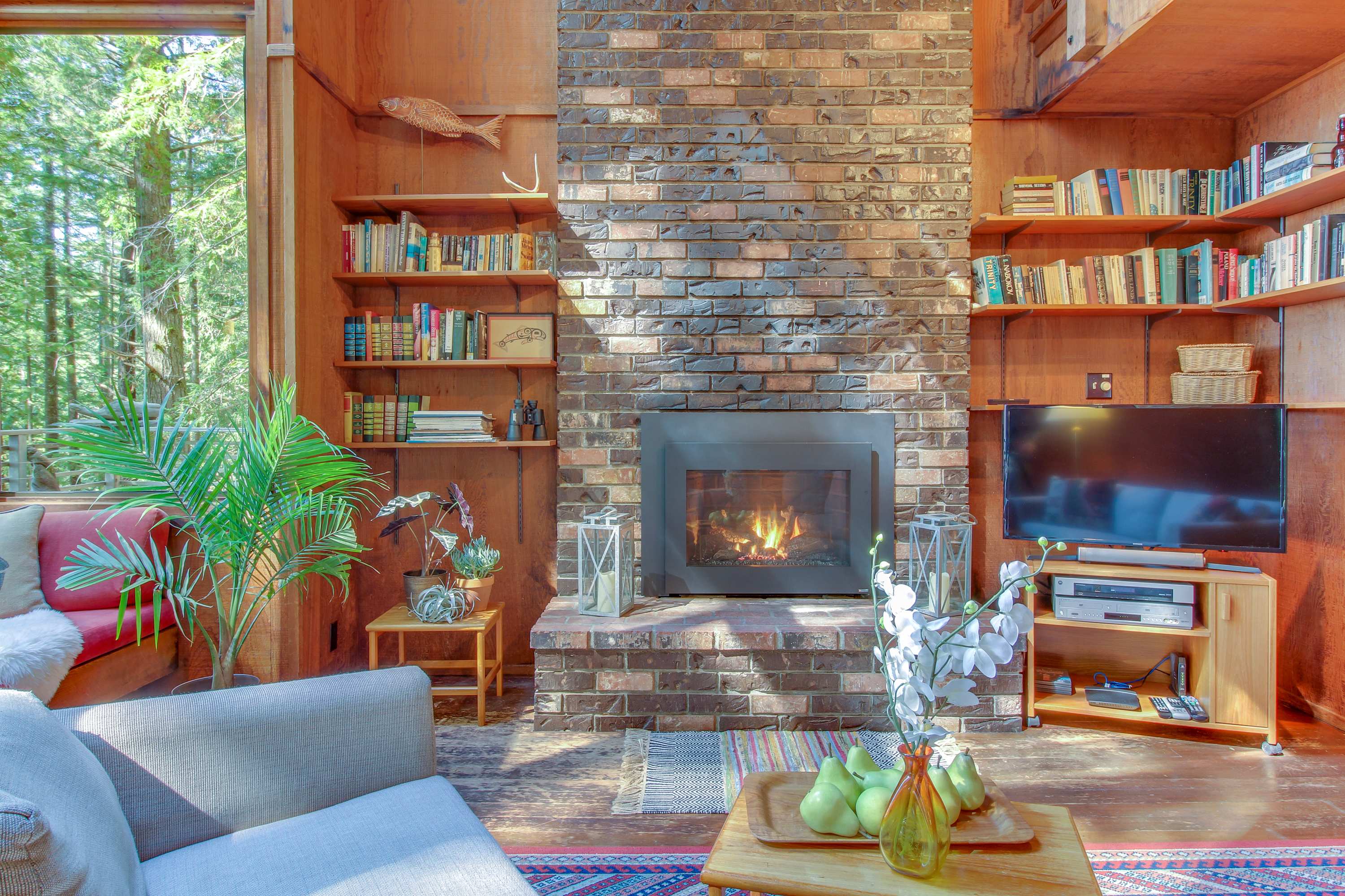 Cozy up by the gas fireplace in this inviting living room, where nature’s beauty spills in through large windows.