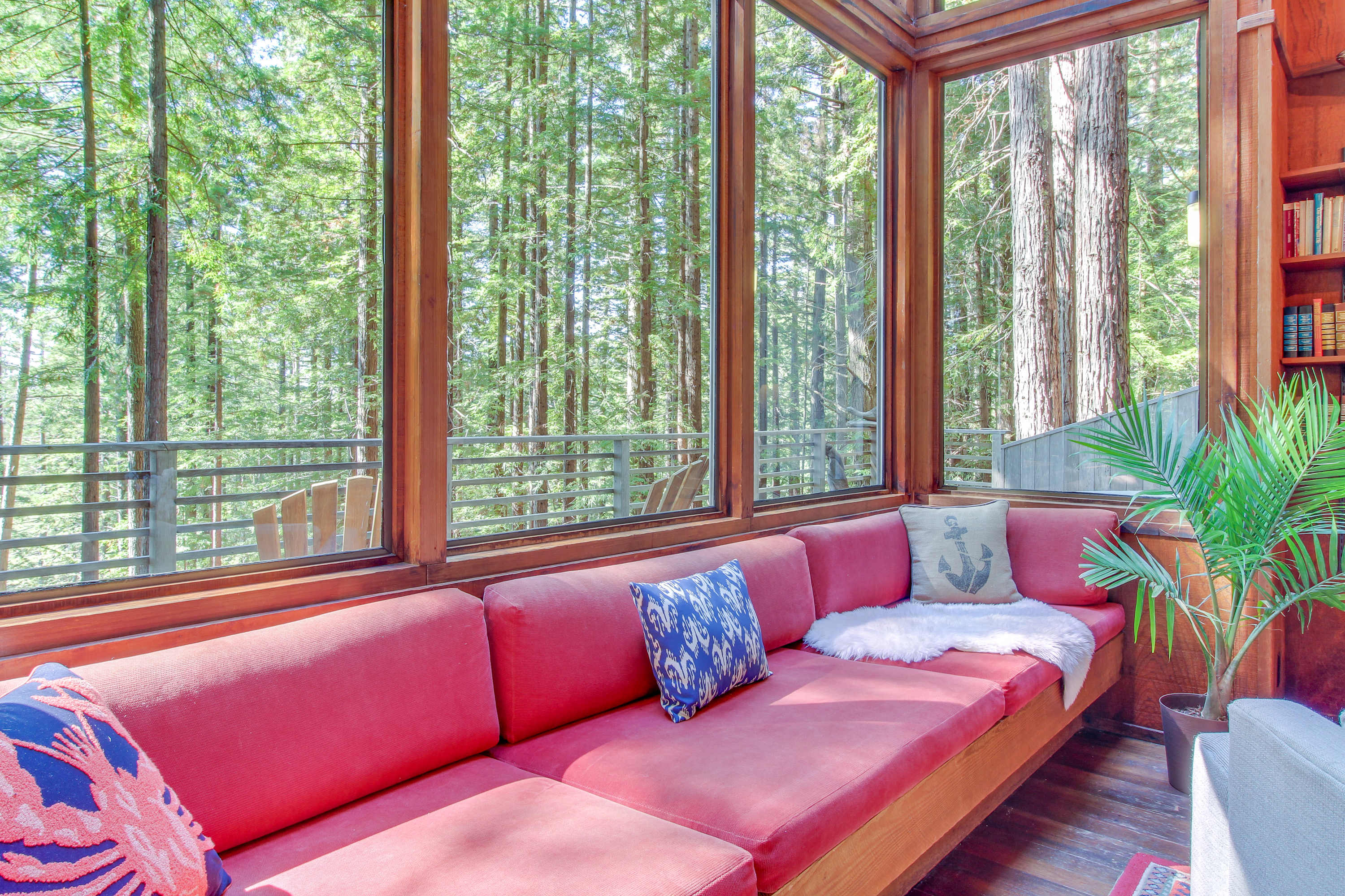 Curl up on the plush red sofa, where you can lose yourself in a good book while enjoying the lush forest views.