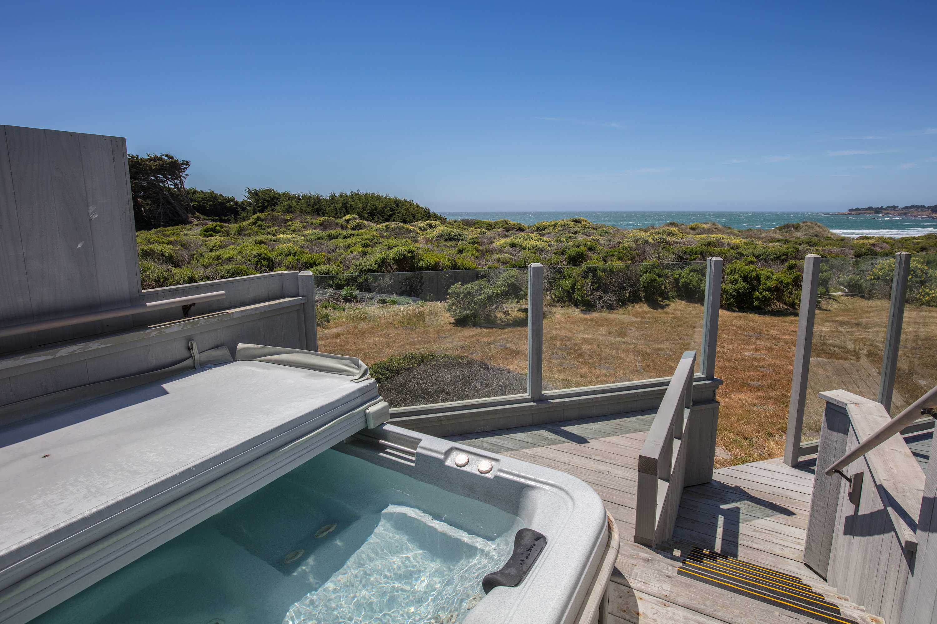 Soak in your private hot tub, surrounded by nature, as you watch waves crash against the shore; pure relaxation awaits.