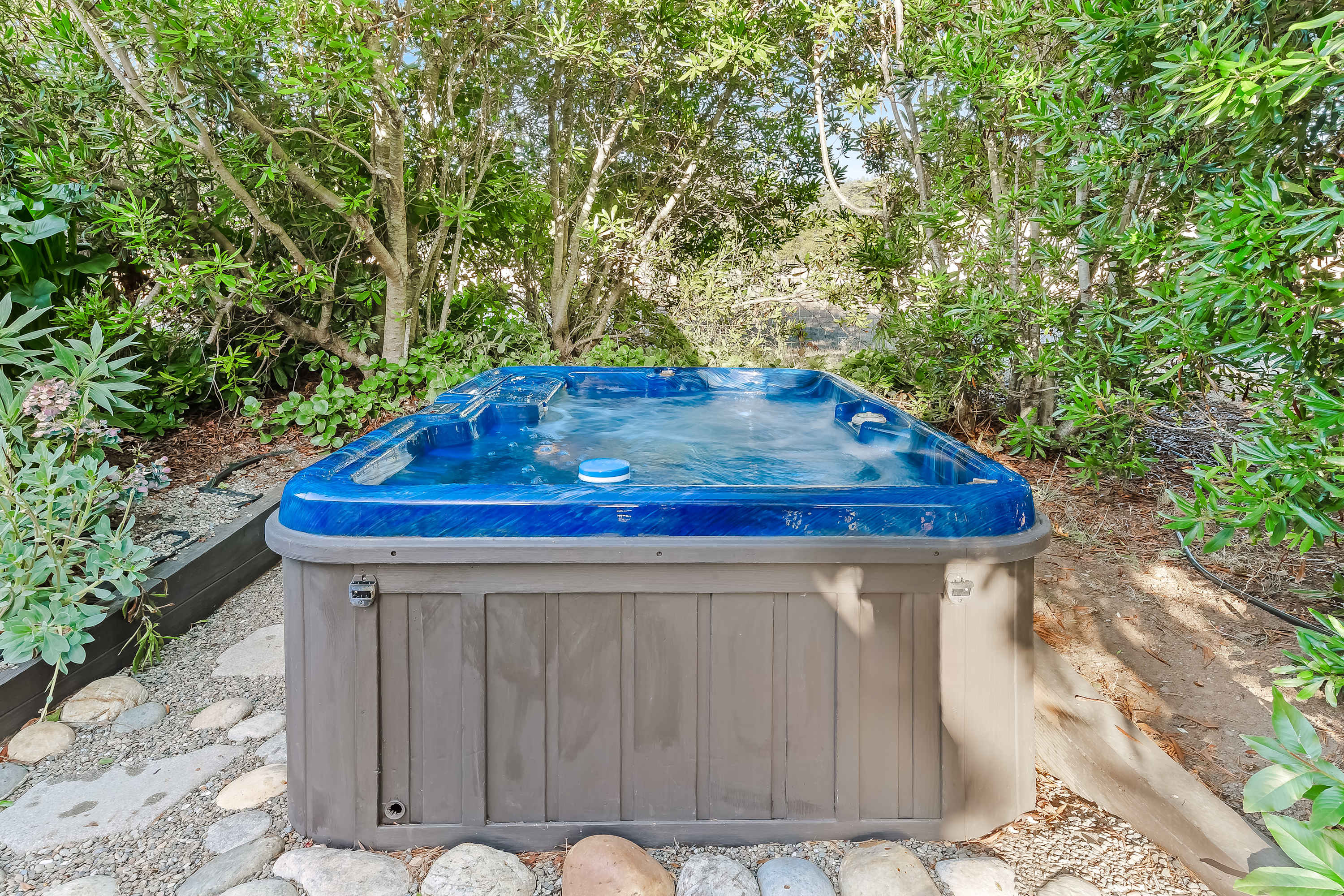 Indulge in soothing soaks in your private hot tub, nestled among lush greenery for a serene escape after a day of exploration.