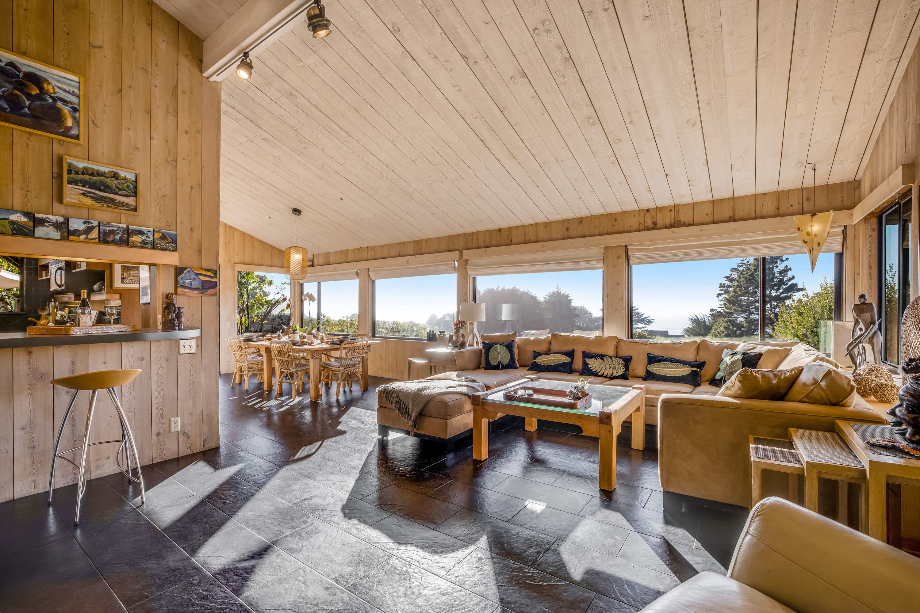 The spacious living room invites you to unwind, with panoramic windows framing the beauty of nature outside.