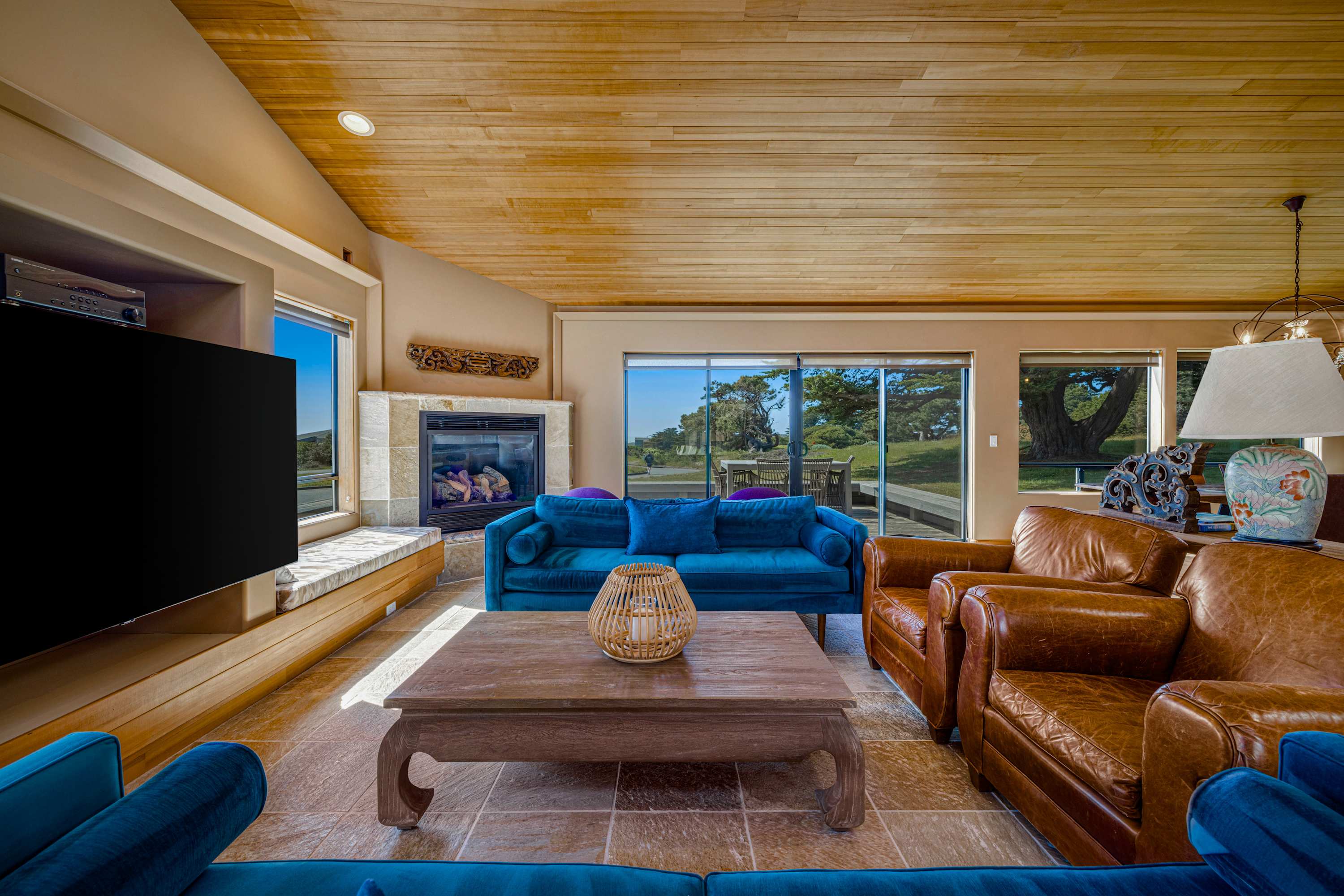 Leather armchairs and a cowhide rug anchor the seating area — the glass fireplace warms movie nights when the fog rolls in.