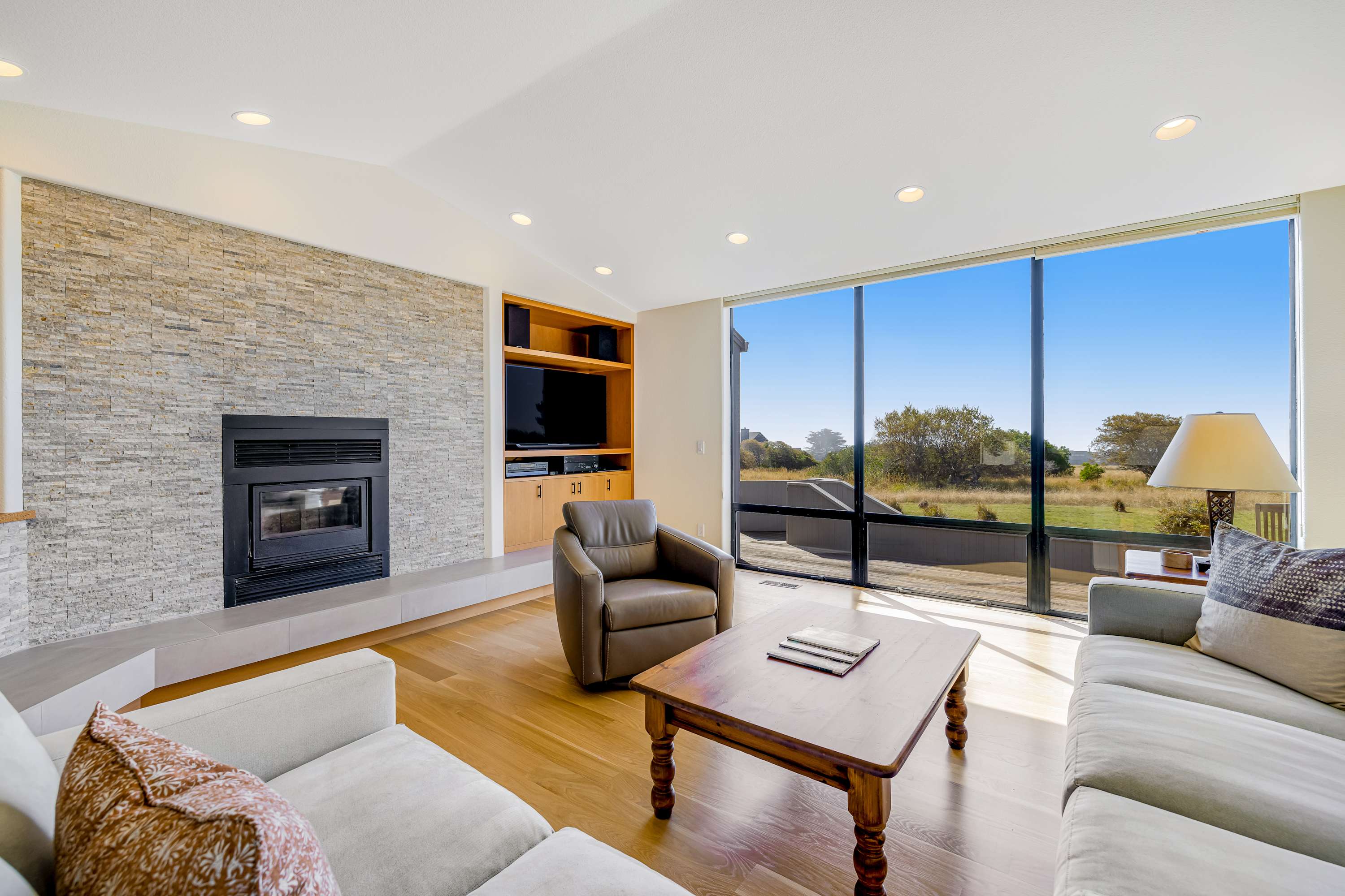 The living room invites you to unwind by the fireplace, where panoramic windows frame stunning coastal vistas.