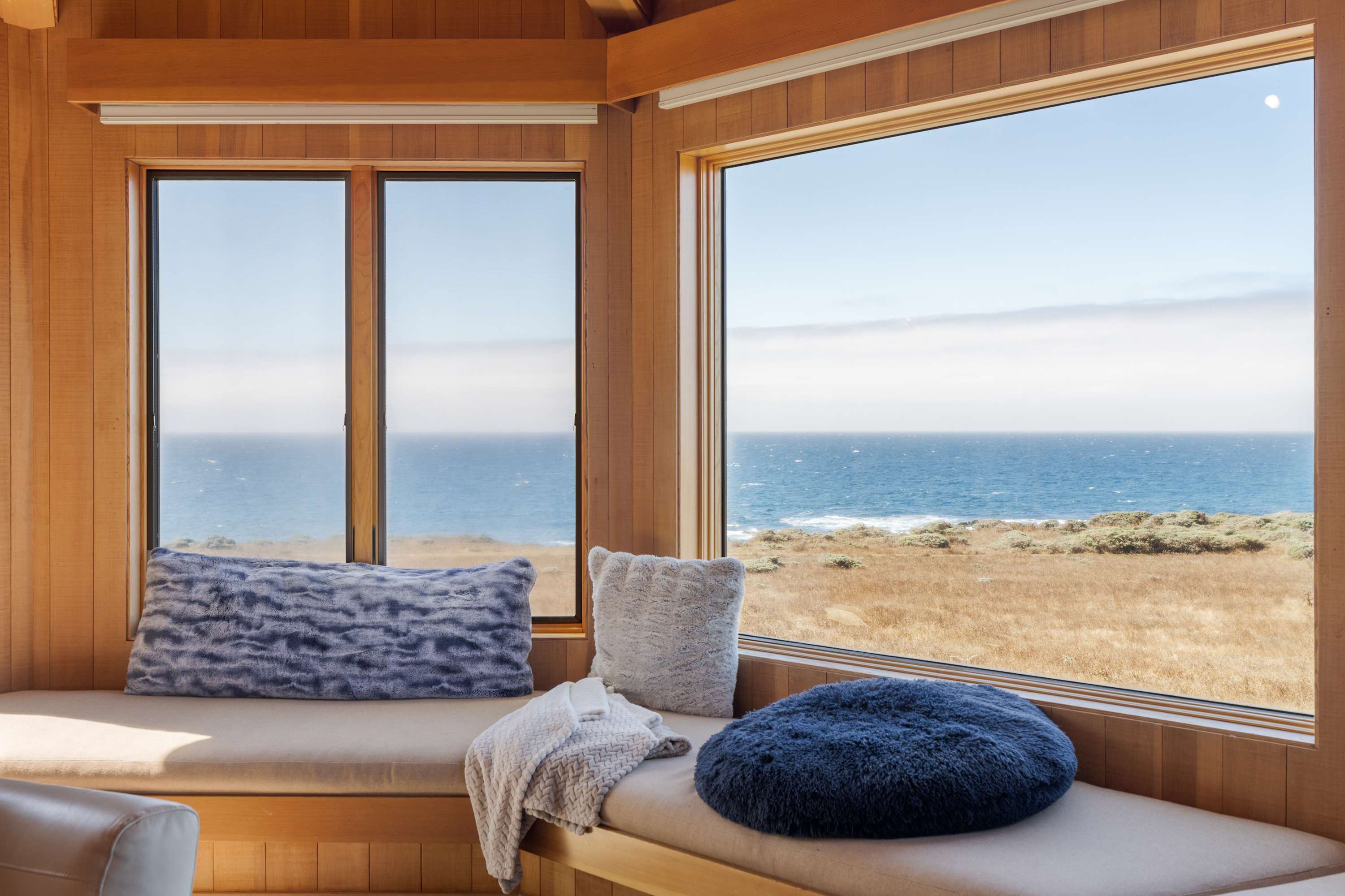 Curl up on the window seat at White Waters with the blue cushions and watch the surf line run past the meadow grass.