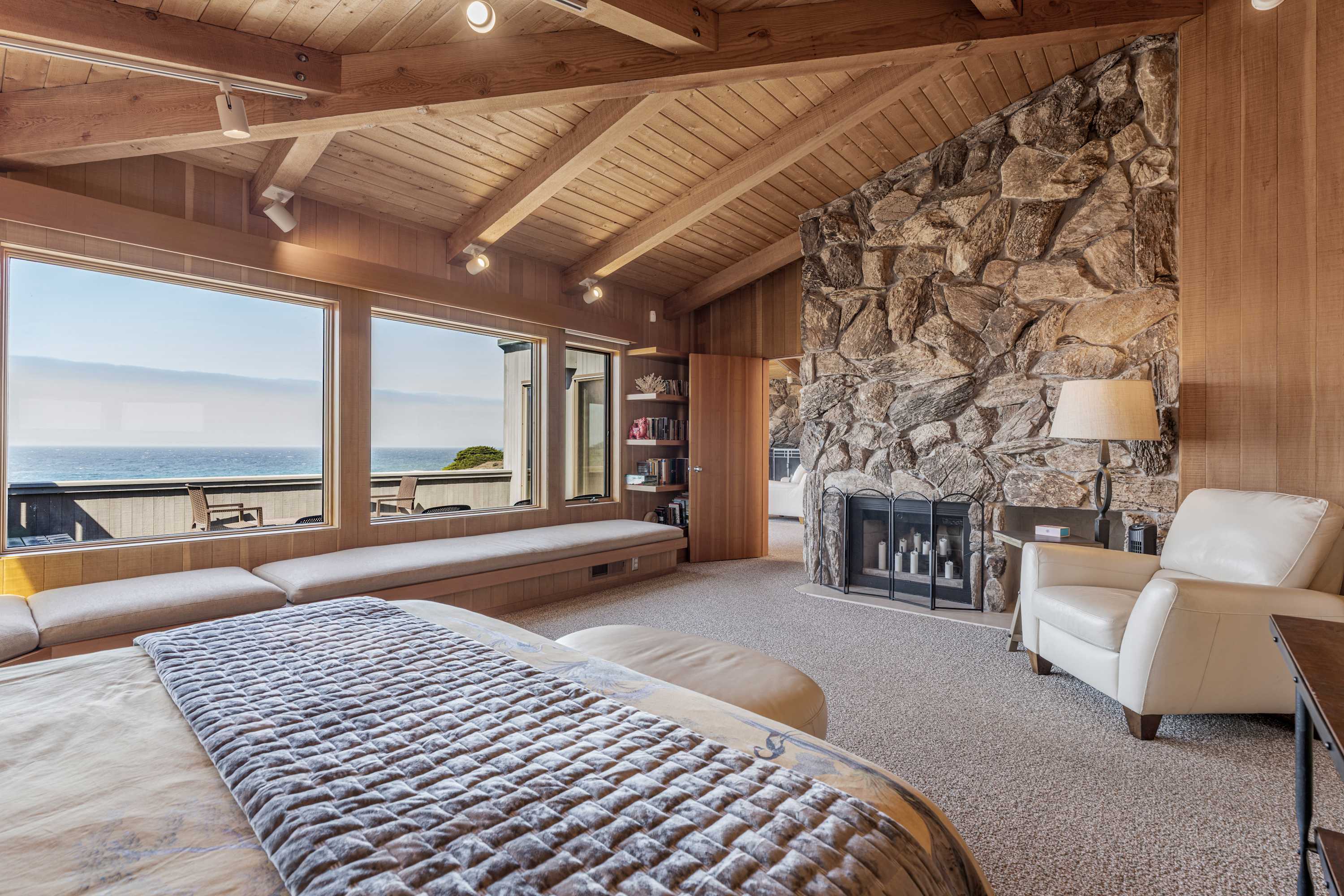 Stretch out on the long built-in bench while the stone fireplace, leather recliner, and cloud-white surf share the room.