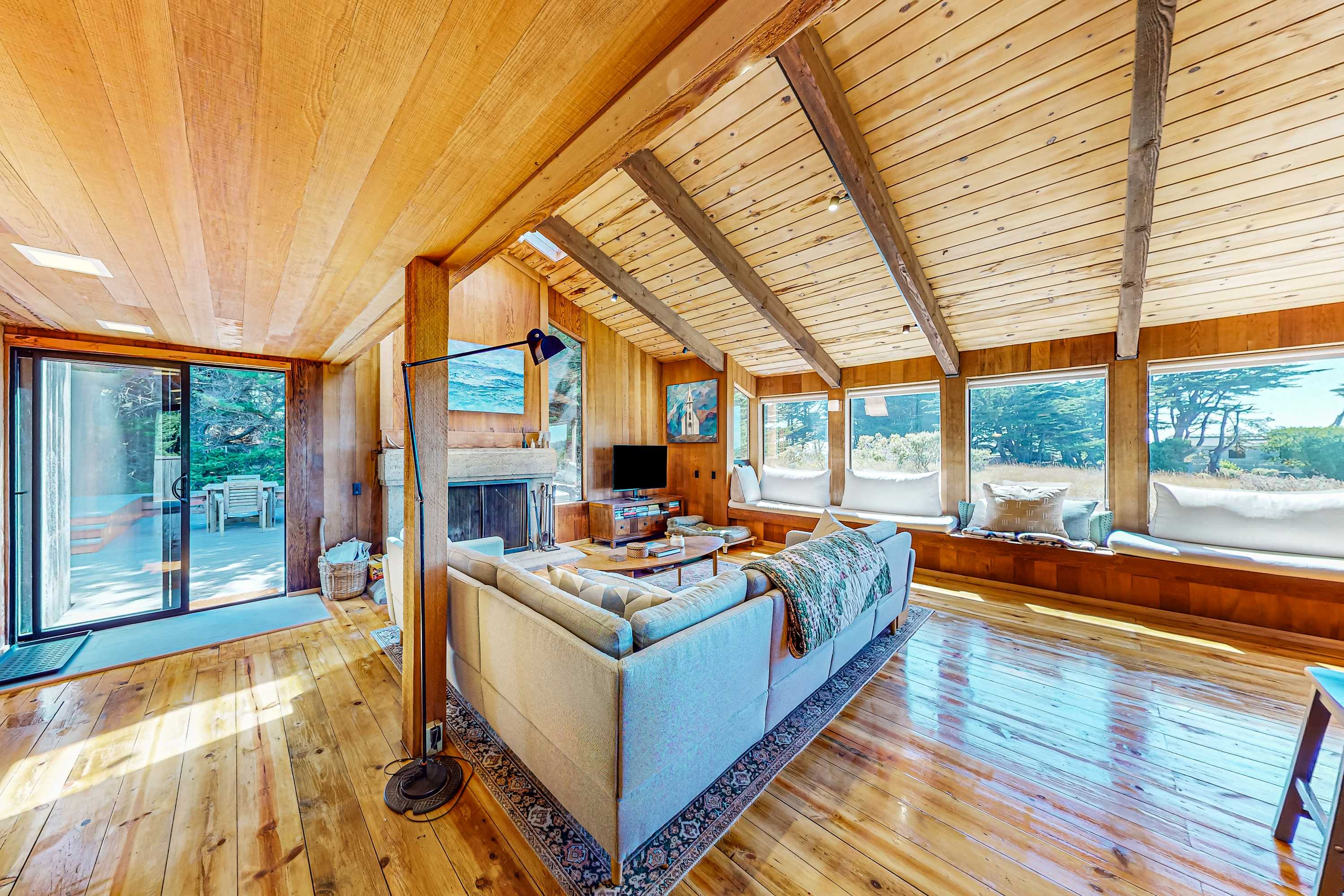 Gather around the wood-burning fireplace in this sunlit living area, perfect for cozy evenings with friends and family.