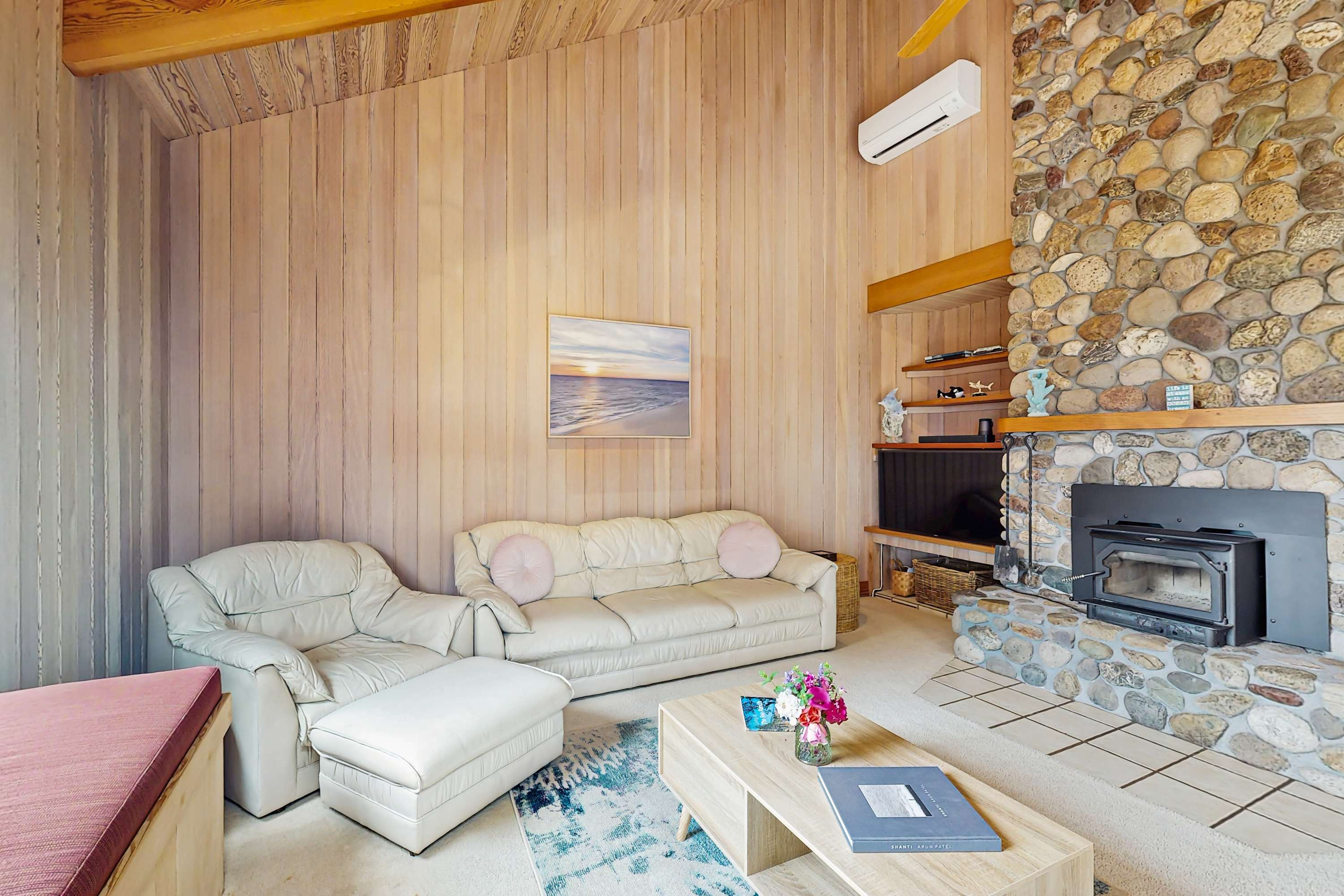 Enjoy movie nights or cozy conversations in this spacious living room, featuring a stone fireplace and ample seating.
