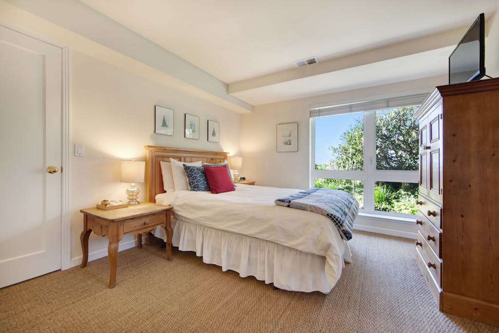 Drift off in this serene queen bedroom with a picture window framing lush garden views.