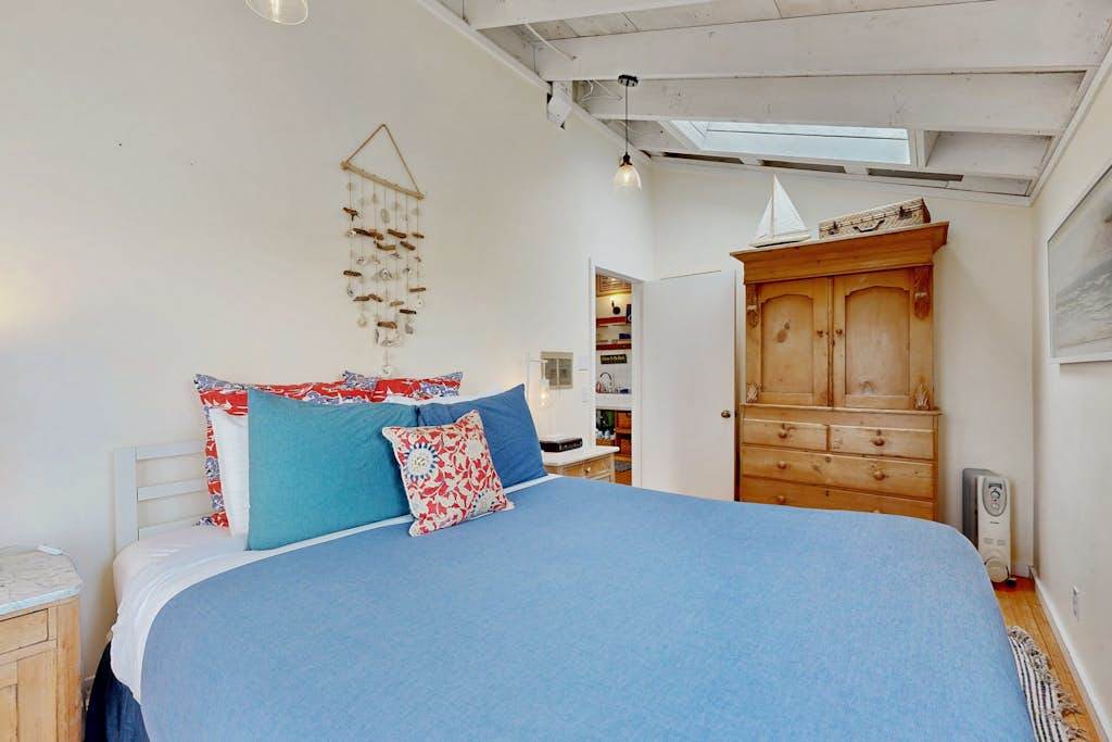 Wake to soft light filtering into your cozy bedroom, appointed with a wooden armoire and beachy accents throughout.