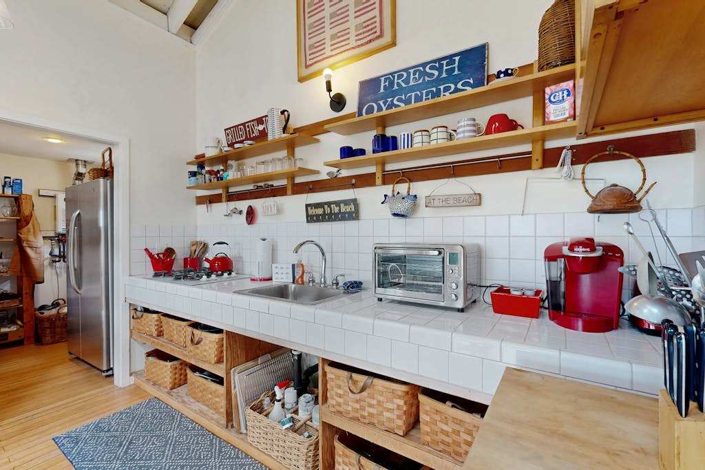 Well-equipped counter with coffee maker, toaster oven, and stainless appliances — everything you need for your coastal morning routine.